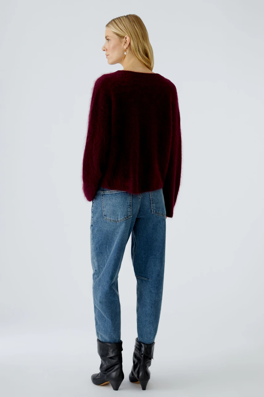 Damen-Pullover: Frau trägt einen burgunderfarbenen, flauschigen Pullover mit lässigen Jeans.