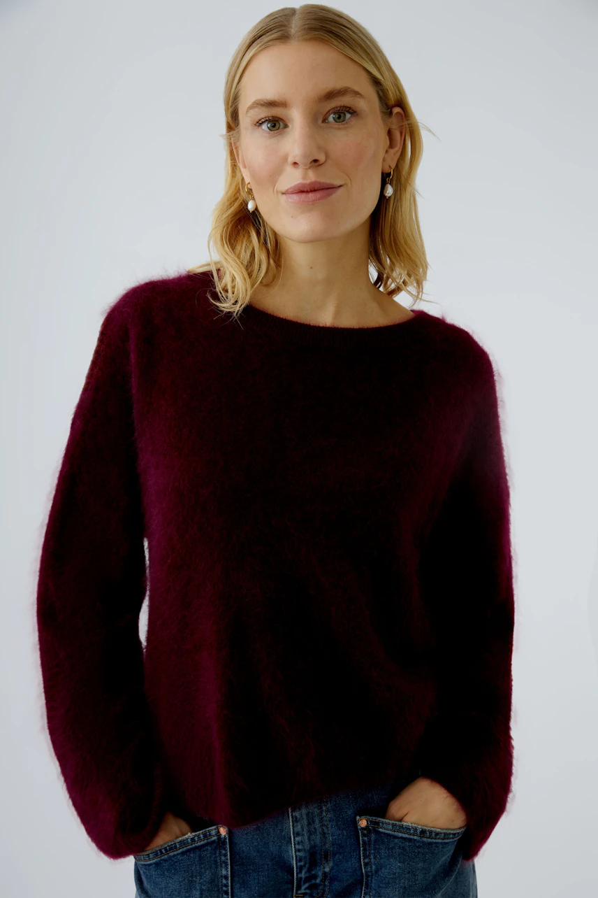 Damen-Pullover in dunklem Rot: Frau mit lässigem Look, trägt einen weichen, lockeren Pullover.