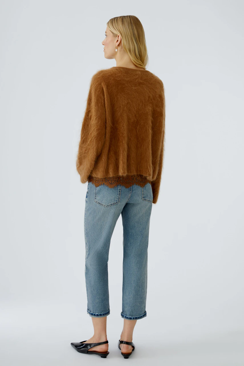 Casual women's pullover: A woman in a cozy brown pullover with a relaxed fit and lace hem.