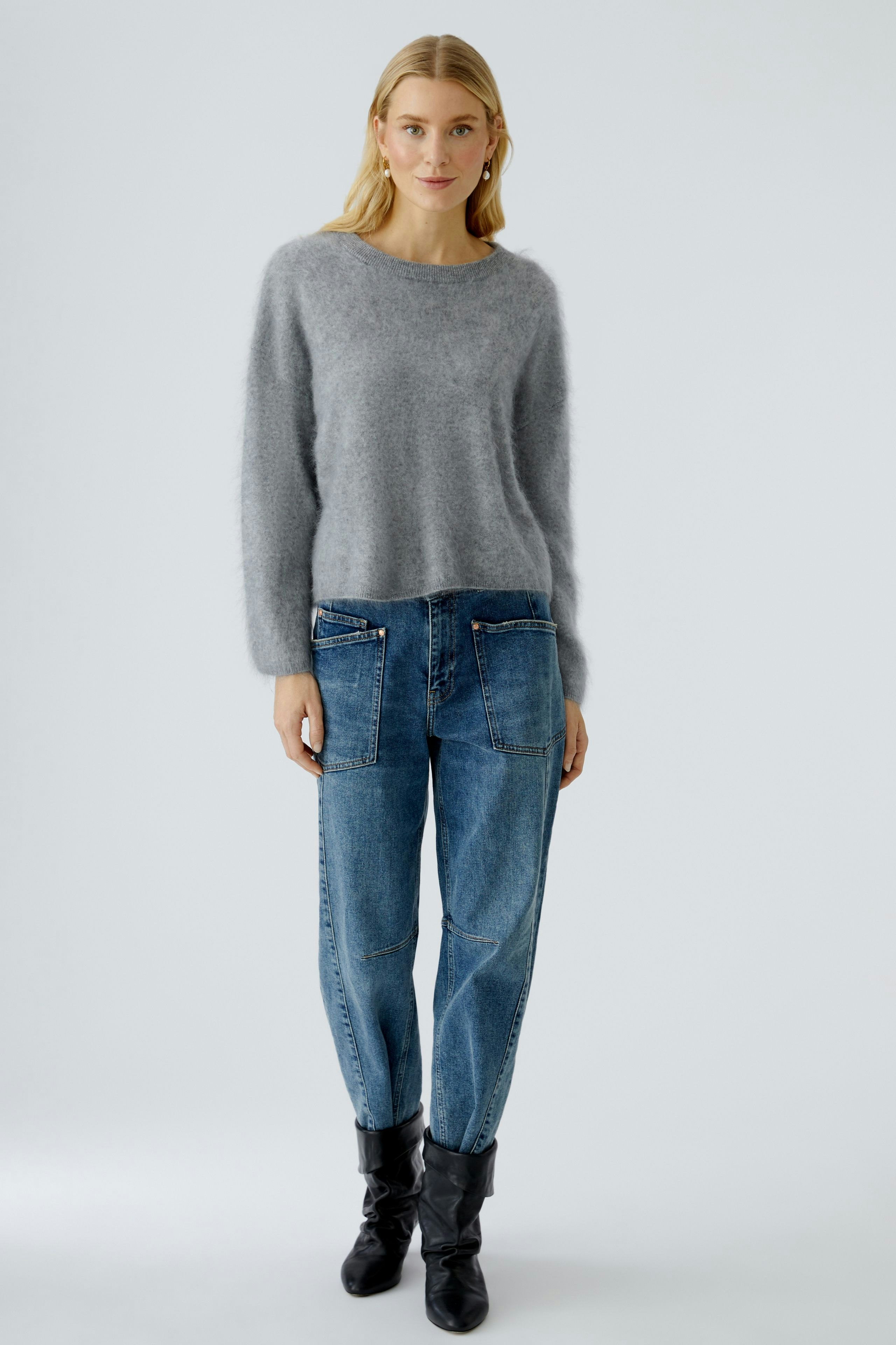 Cozy women's pullover: A woman in a soft gray pullover paired with relaxed-fit jeans.
