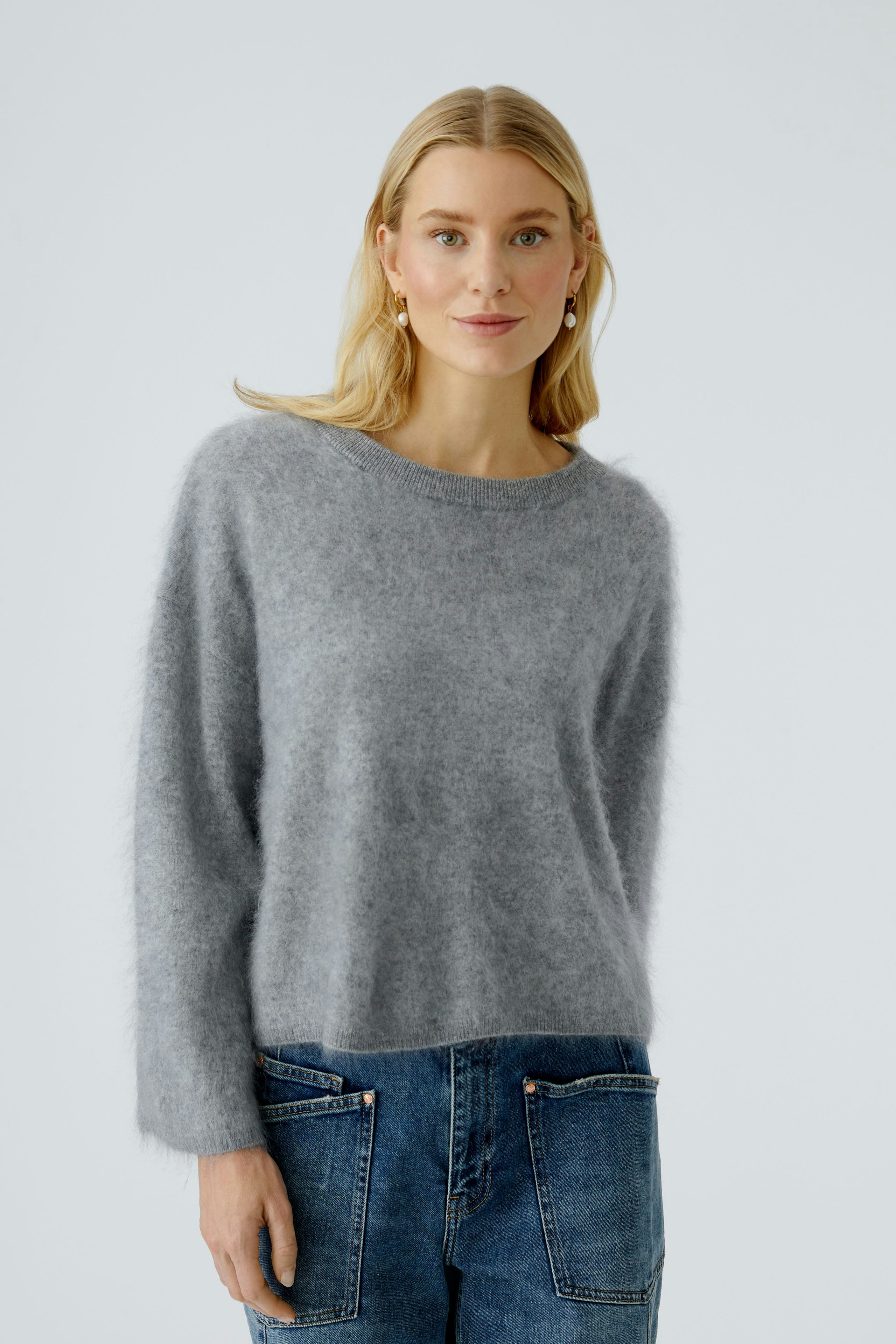 Casual women's pullover: Young woman in a soft gray pullover with relaxed fit and stylish jeans.