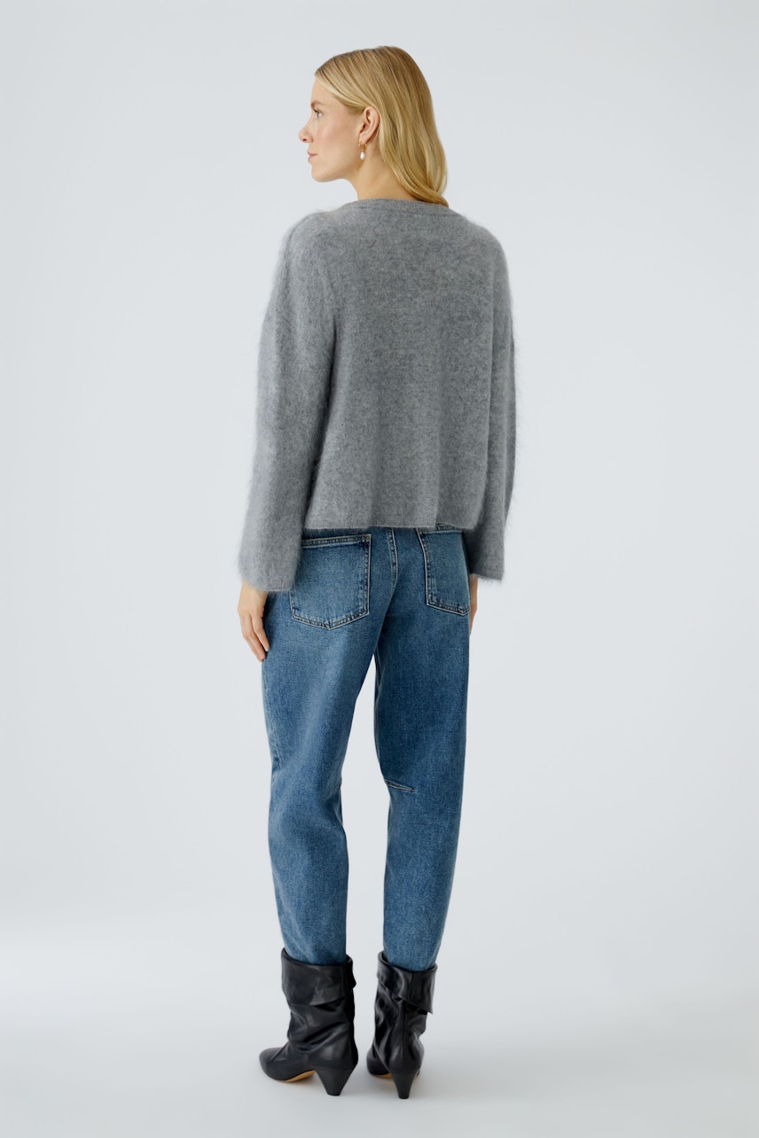 Casual women's pullover: A woman in a soft gray pullover paired with relaxed jeans.