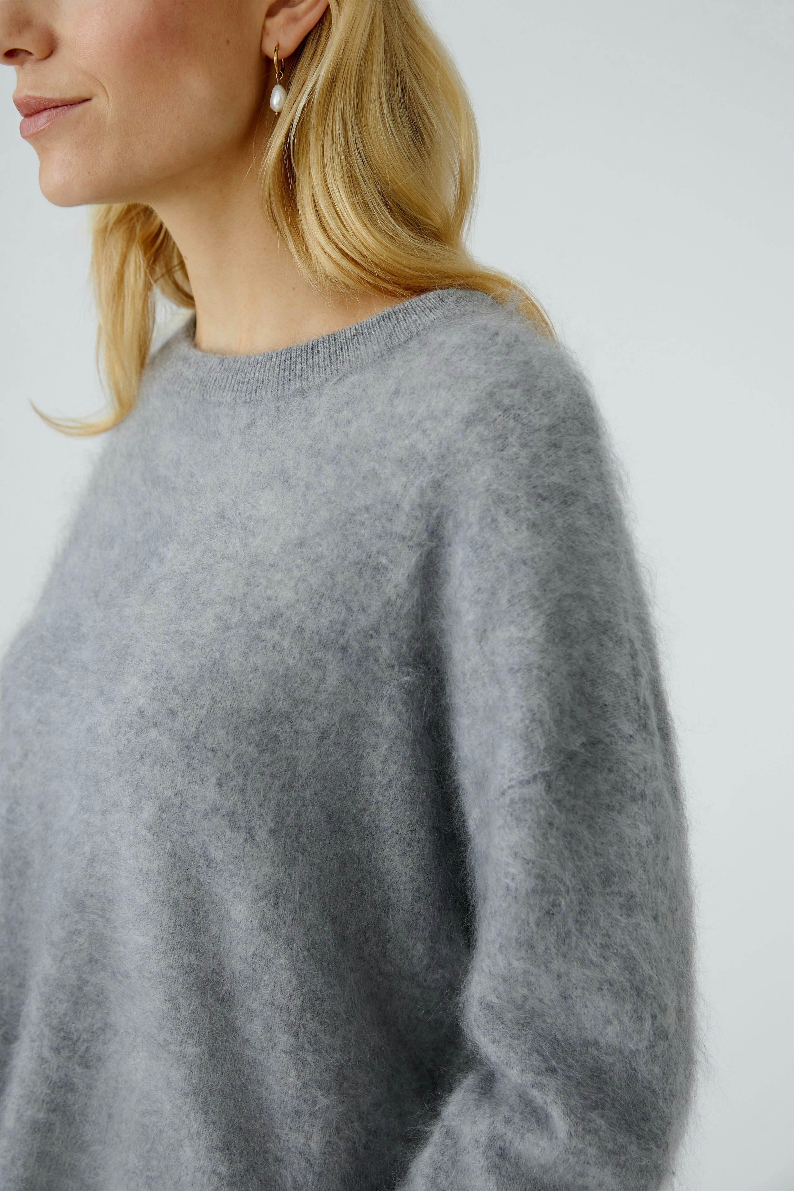Casual women's pullover: A woman in a soft gray pullover with a relaxed fit and round neckline.