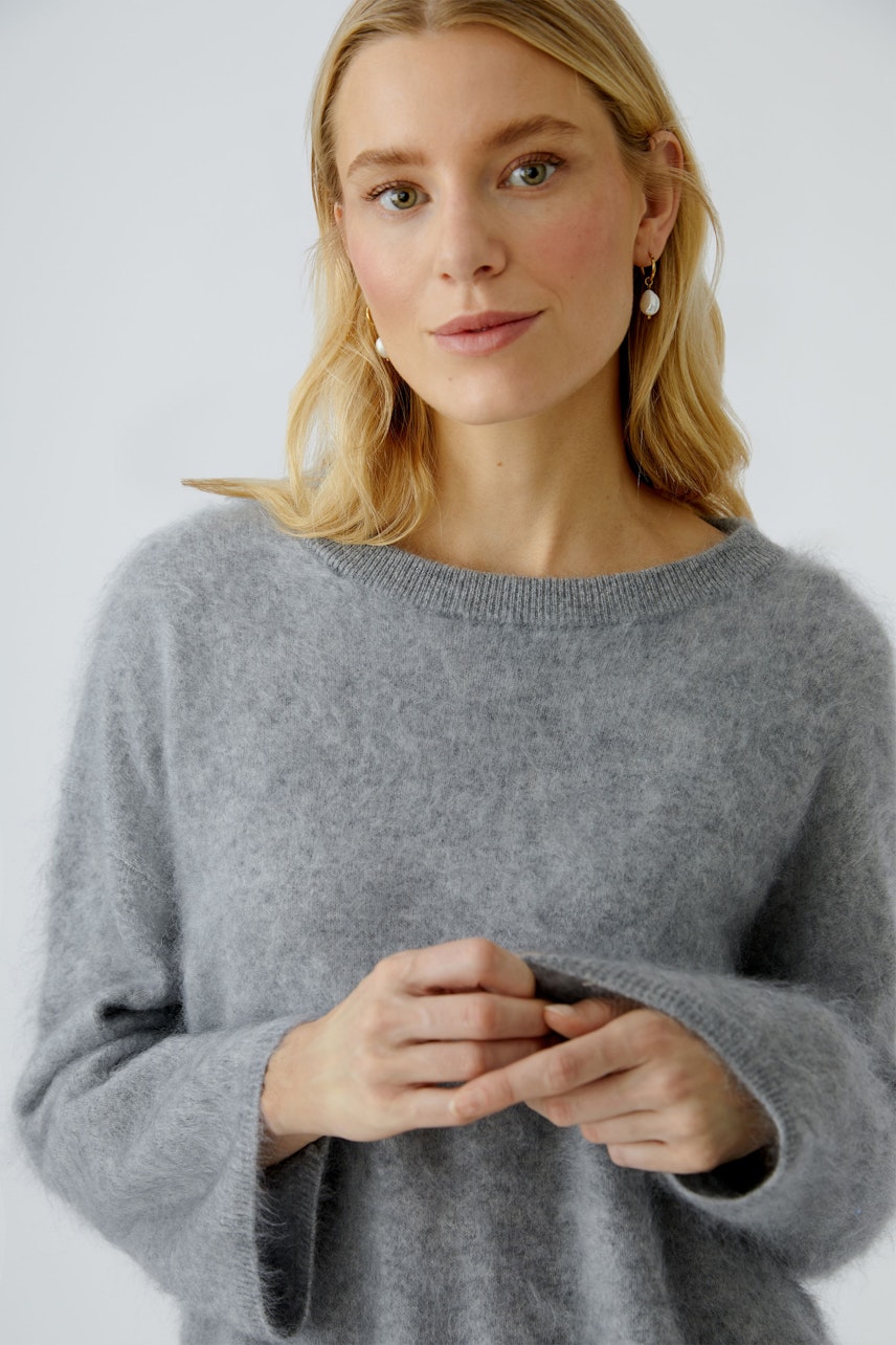 Casual women's pullover: A woman in a soft gray pullover with relaxed sleeves, looking approachable.