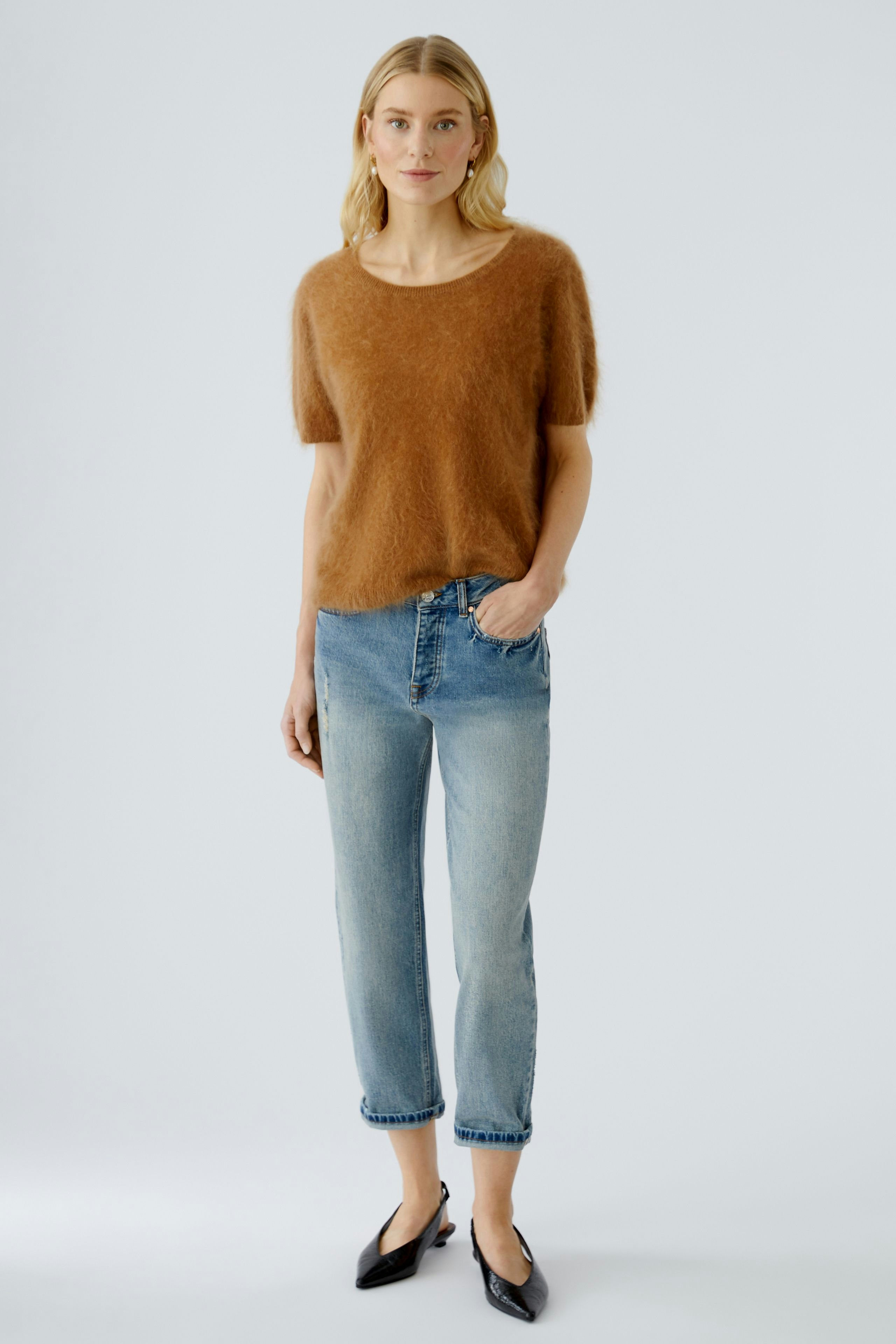 Casual women's pullover: Young woman in a soft brown pullover paired with light blue jeans.