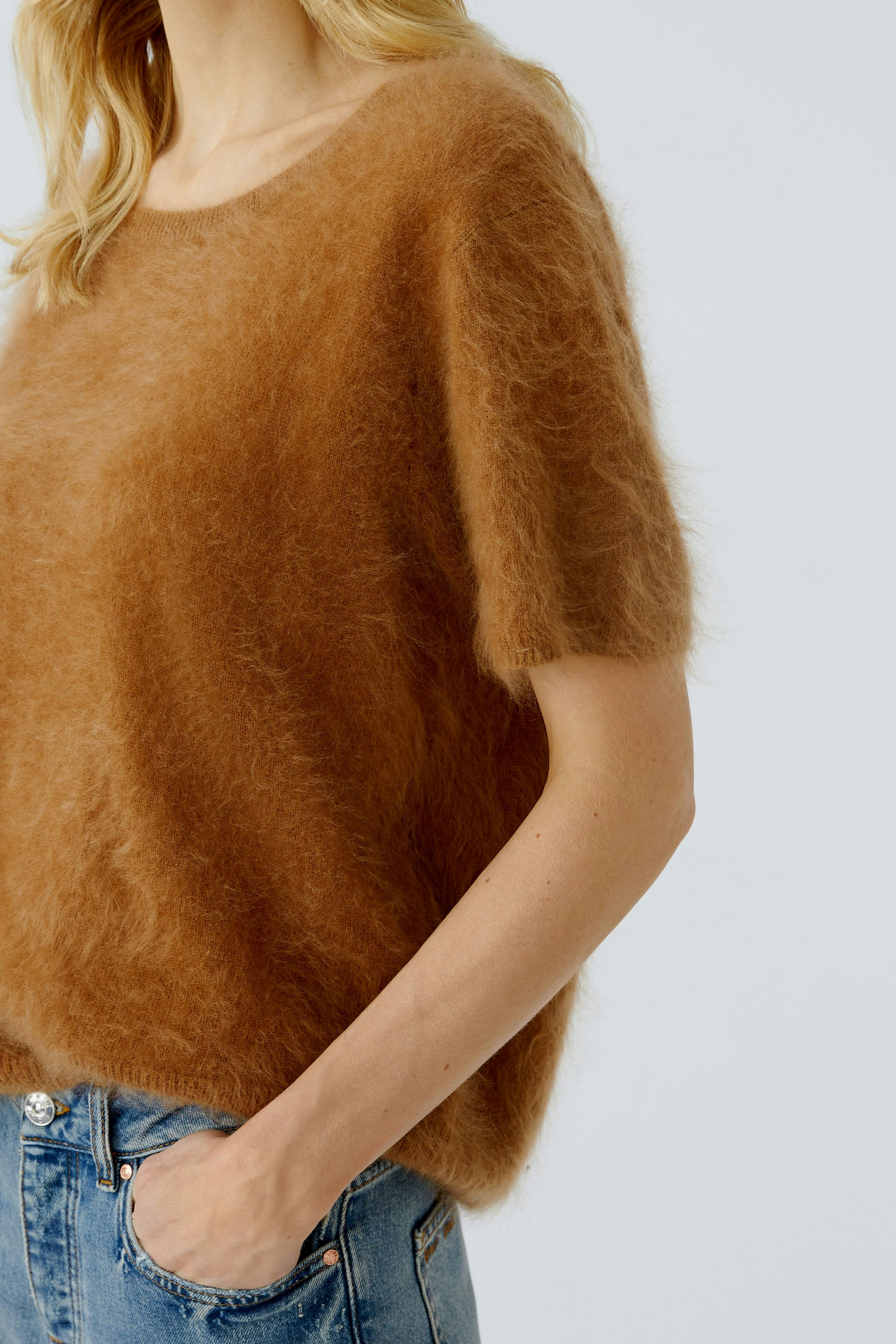 Casual women's pullover: A woman in a soft brown pullover with short sleeves, paired with denim.