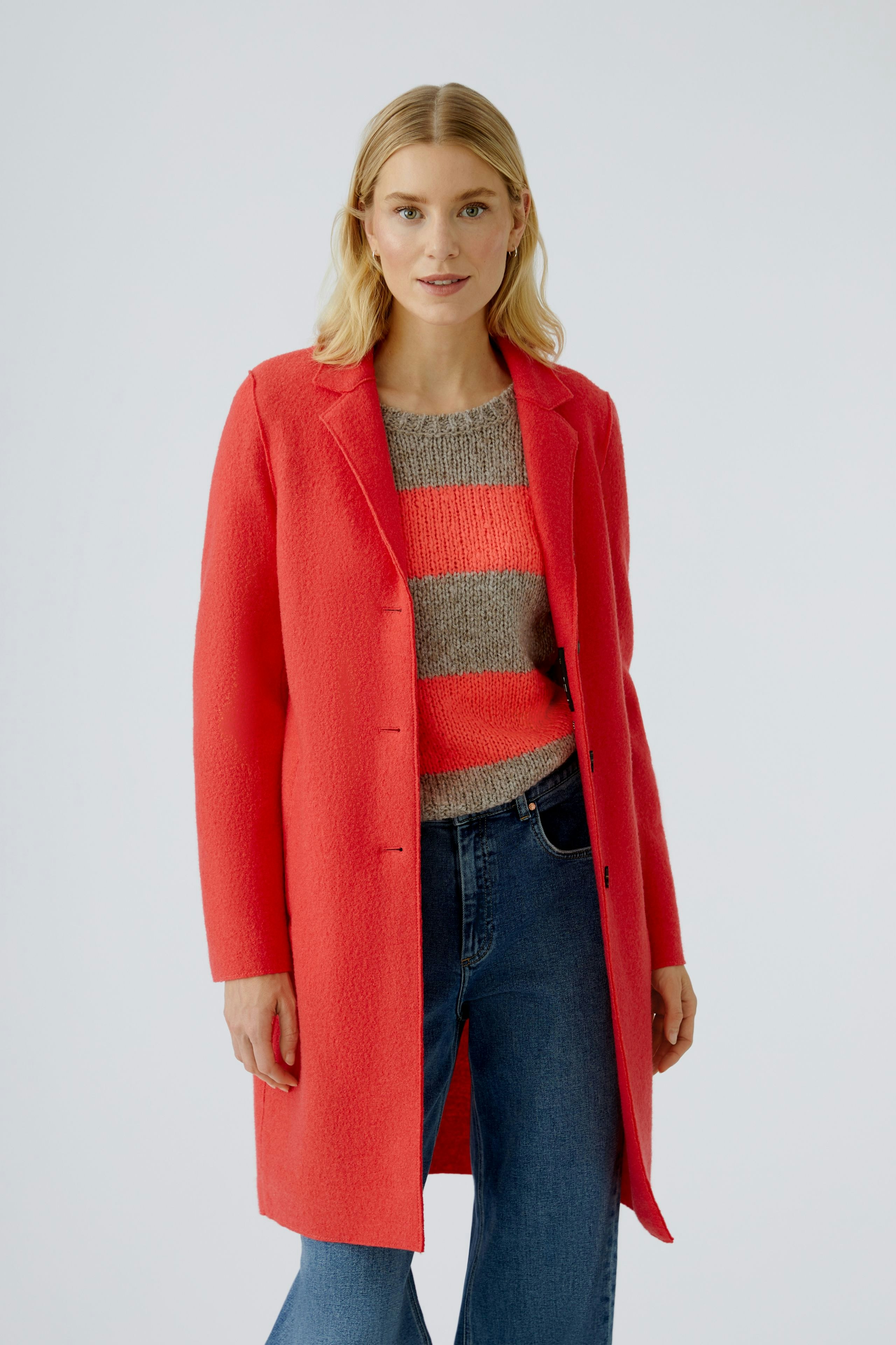 Damen-Wollmantel in leuchtendem Rot, kombiniert mit gestreiftem Pullover und Jeans.