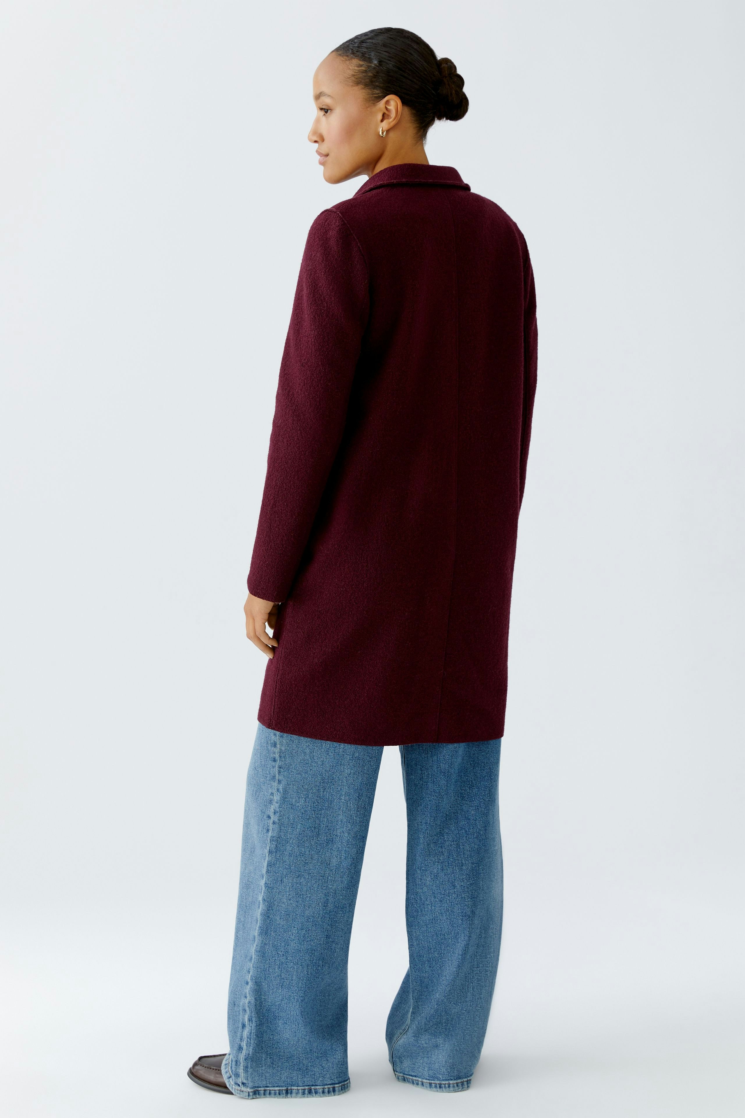 Stylish women's wool coat in burgundy, paired with wide-leg jeans, showcasing a modern look.