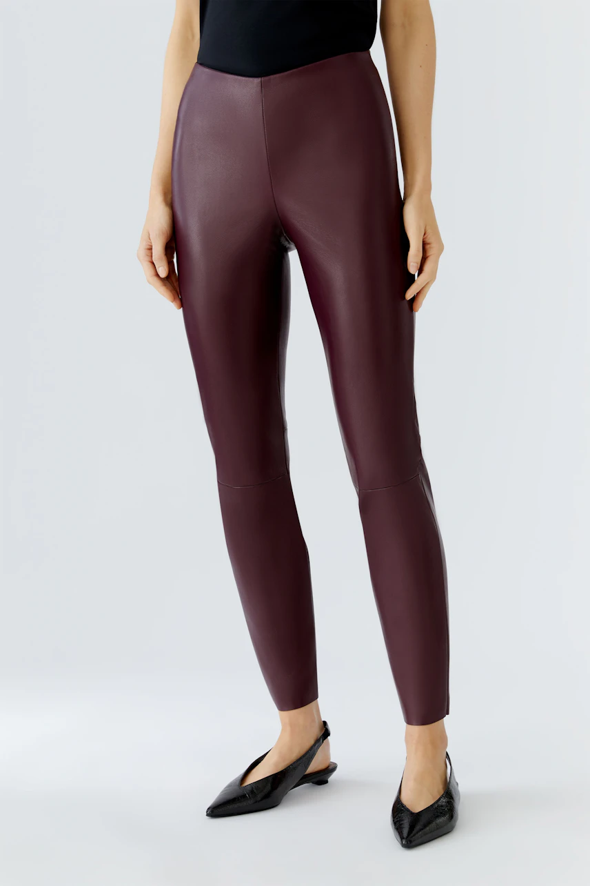 Trendy women's leggings in a rich burgundy color, styled with a fitted top and sleek shoes.