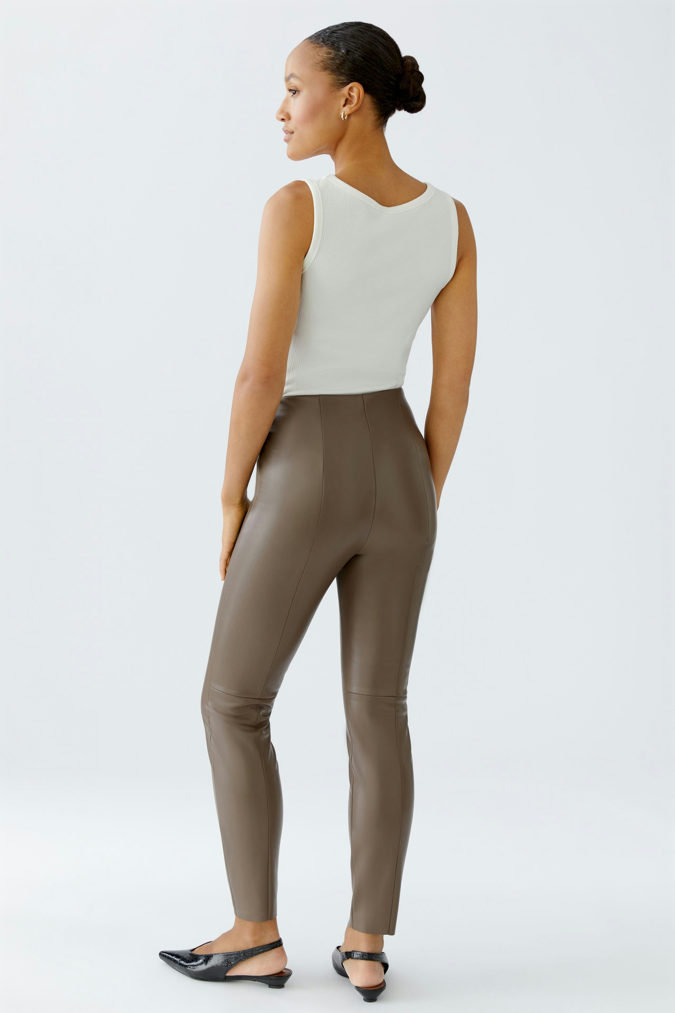 Stylish leggings: Woman in brown leggings and white top, showcasing a modern, casual look.
