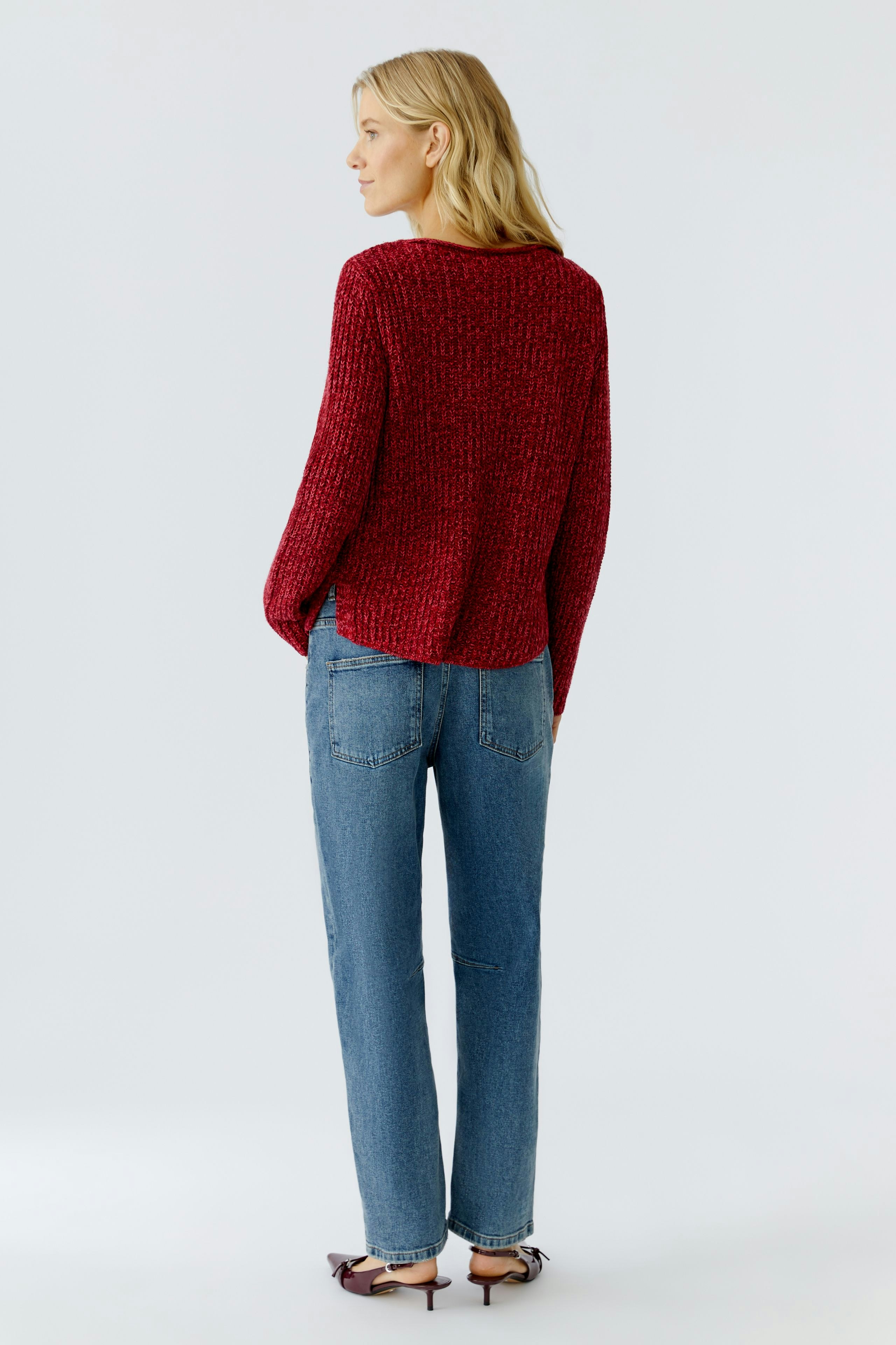 Casual women's pullover: A woman in a red textured pullover and blue jeans stands with her back to the camera.
