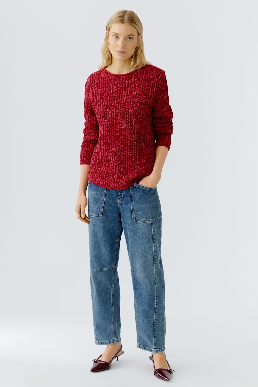 Damen-Pullover: Junge Frau in rotem, strukturiertem Pullover mit lässigen Jeans und schlichten Schuhen.