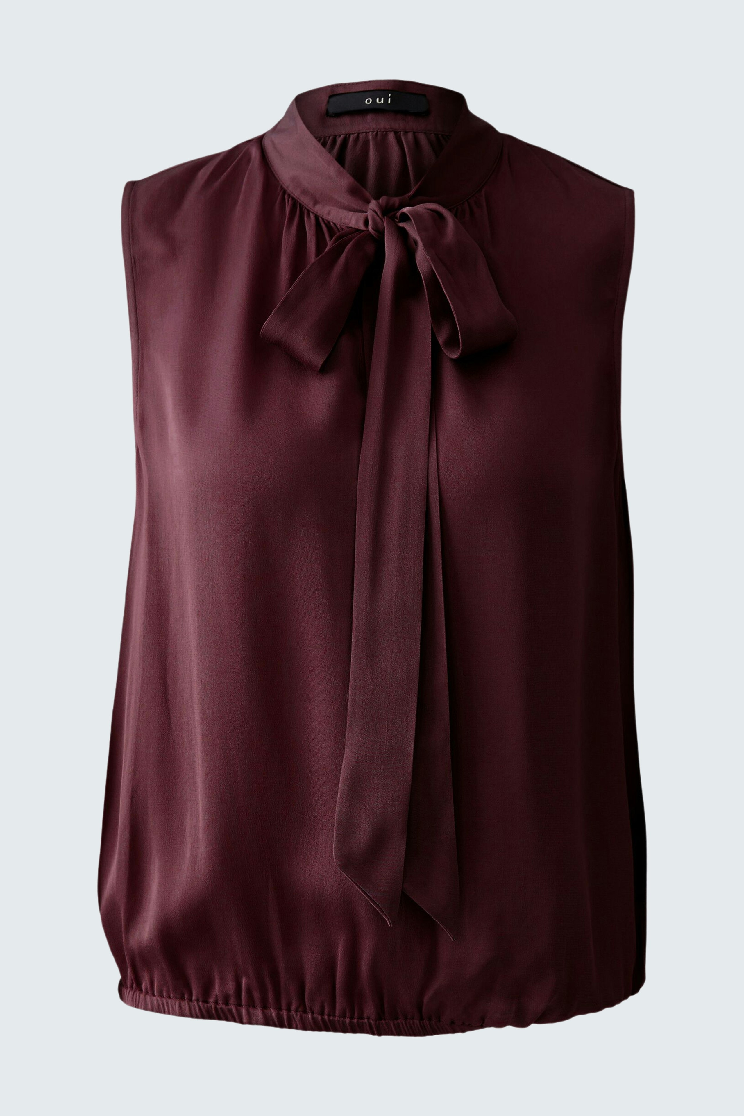 Sleeveless blouse: A woman in a burgundy top with a bow tie and gathered hem, perfect for casual wear.