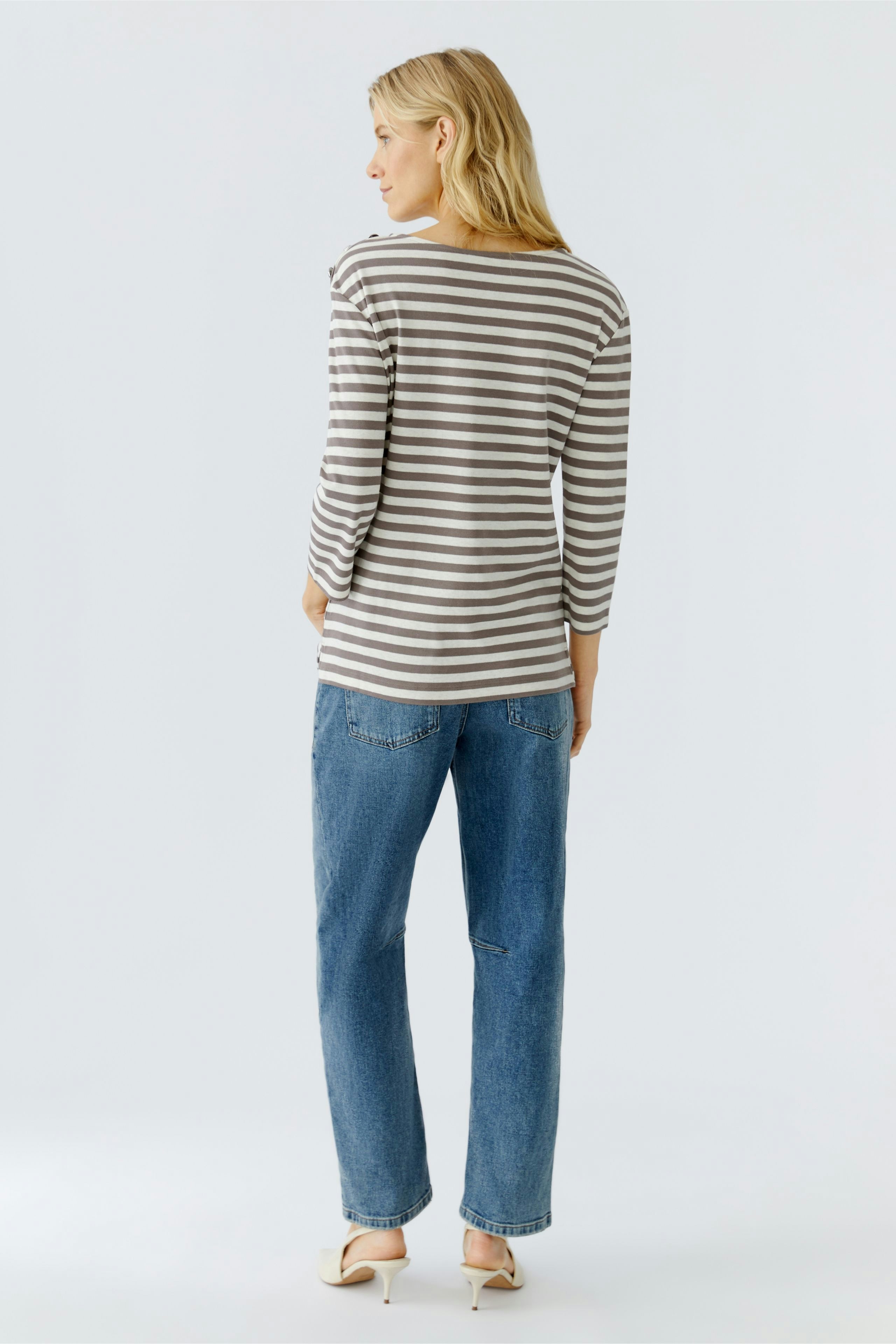 Damen Langarmshirt: Frau trägt gestreiftes Shirt mit lässigem Schnitt und bequemen Jeans.