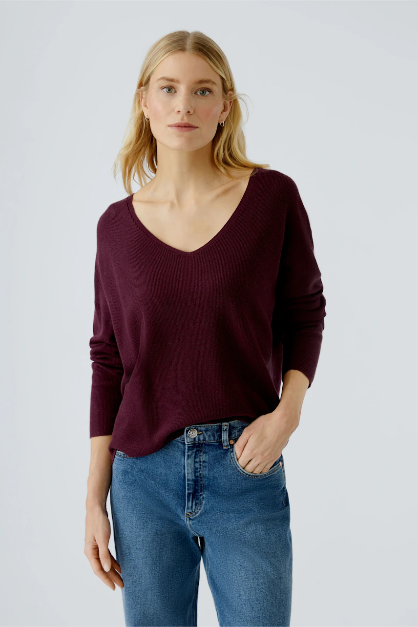 Casual women's pullover: A woman in a deep burgundy pullover with a V-neck and relaxed fit.