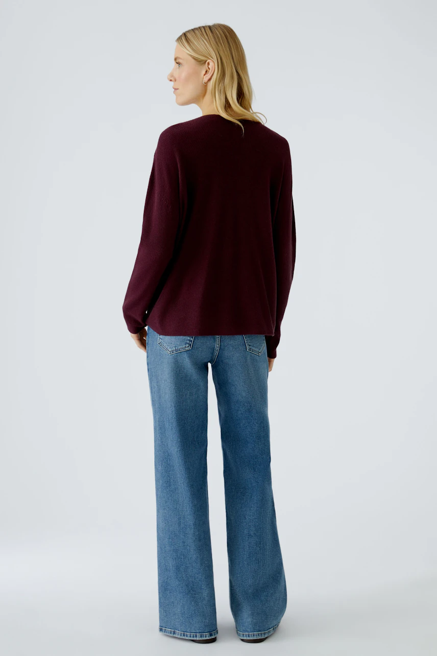 Casual women's pullover in deep burgundy, paired with wide-leg jeans, showcasing a relaxed fit.