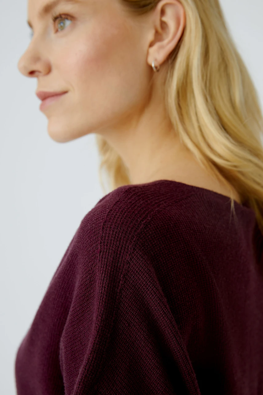 Casual women's pullover: A woman in a deep purple knit pullover with a relaxed fit.
