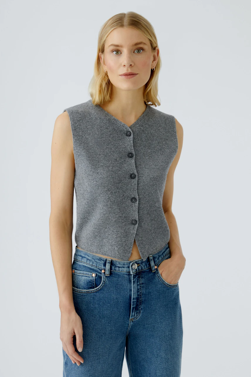 Casual women's cardigan: A woman in a gray sleeveless cardigan with buttons, paired with blue jeans.