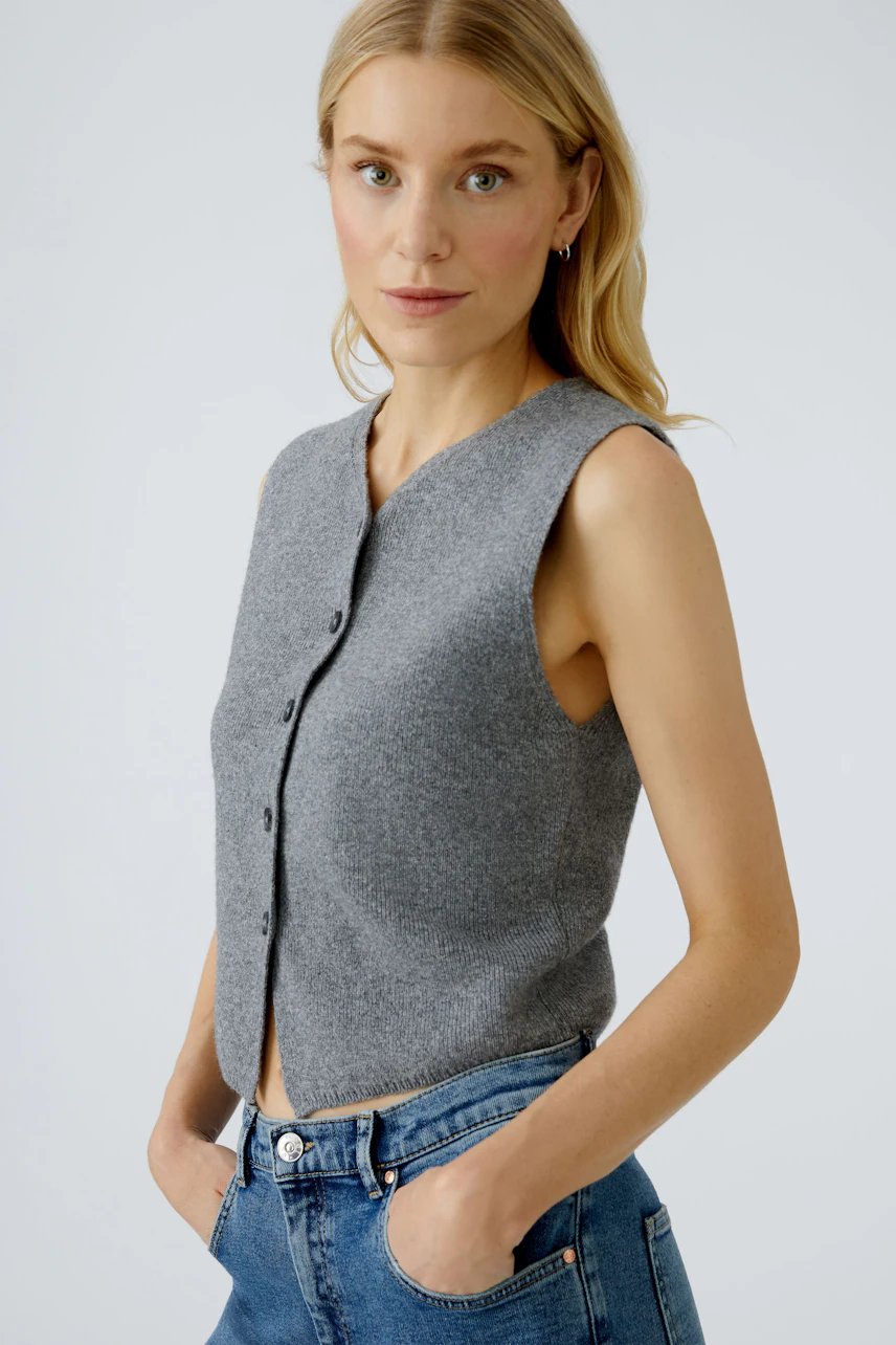 Casual women's cardigan: A woman in a gray sleeveless cardigan with buttons, paired with jeans.