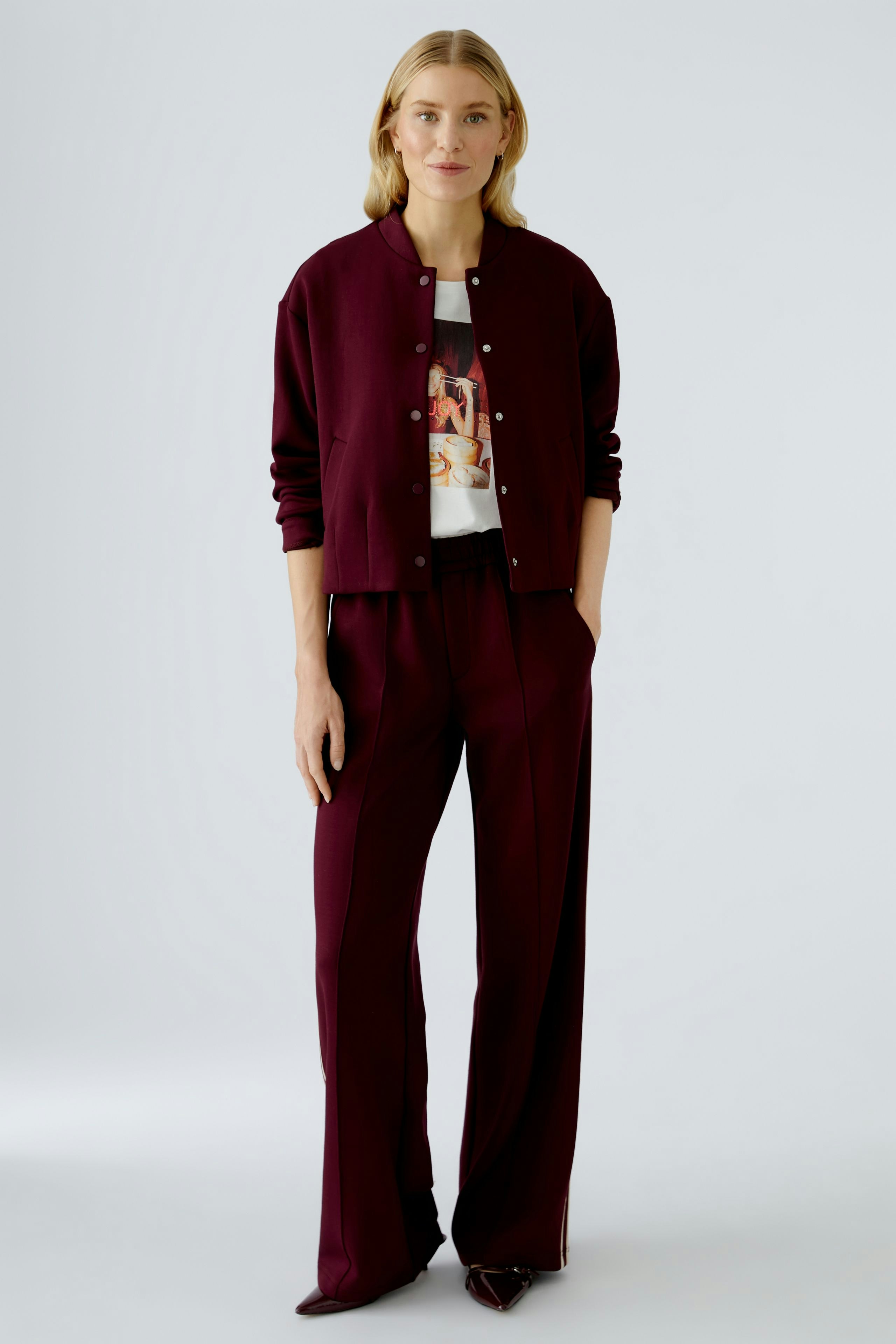 Casual women's joggers: A woman in burgundy joggers paired with a matching bomber jacket and graphic tee.