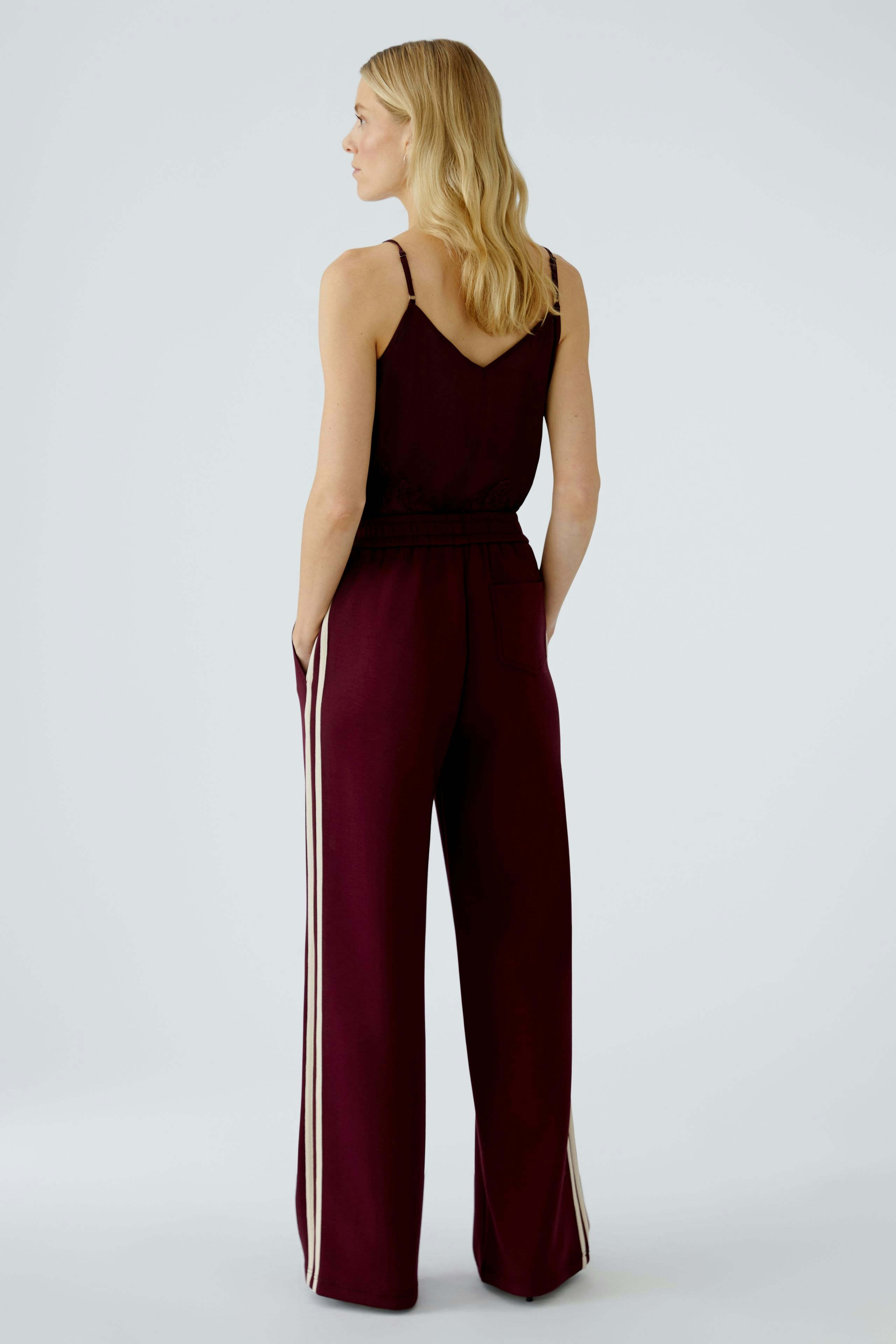 Casual jogger pants: Woman in burgundy joggers with side stripes, showcasing a relaxed fit.