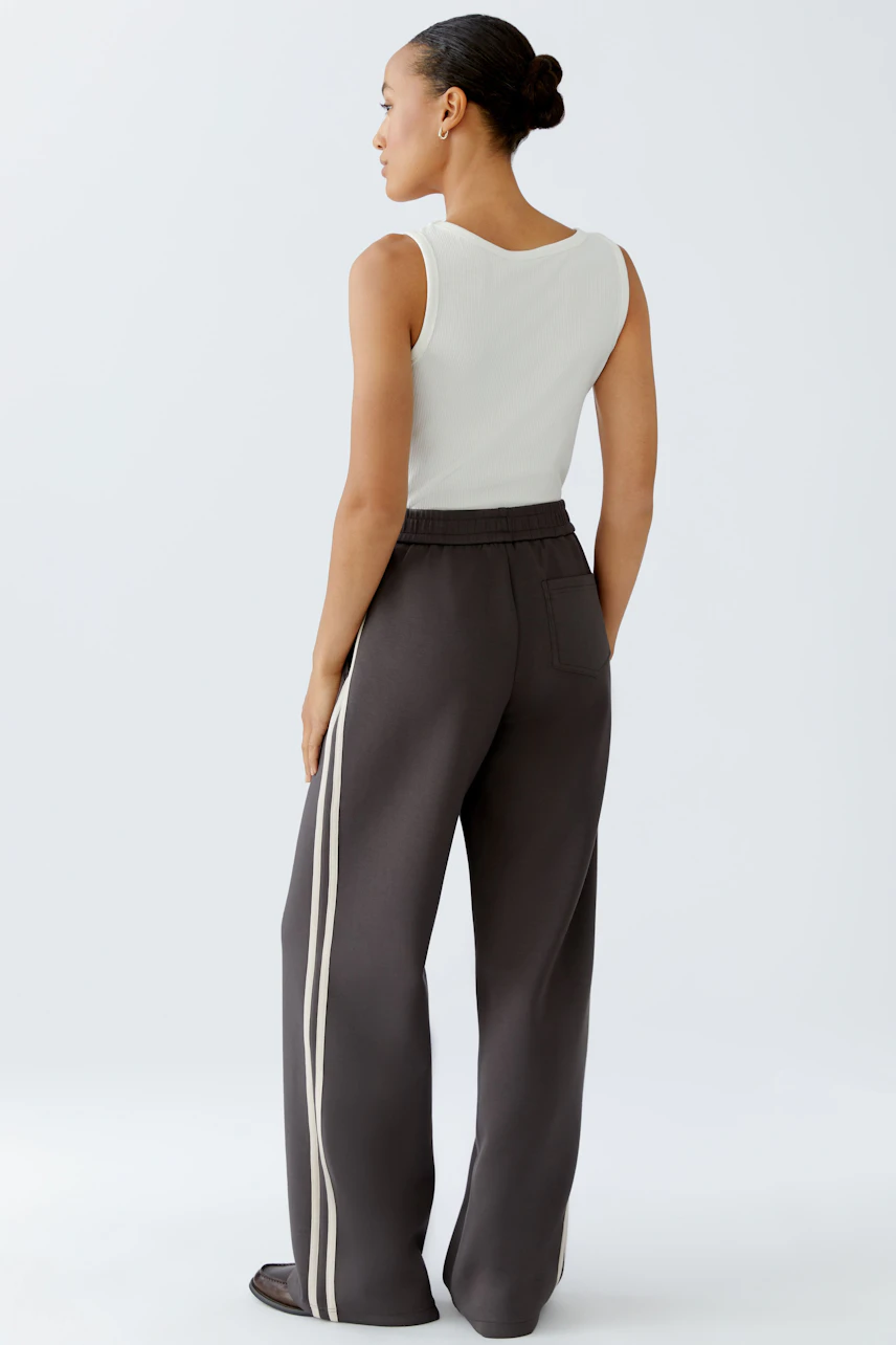 Comfortable joggers: Woman in relaxed-fit joggers with side stripes, showcasing a casual style.