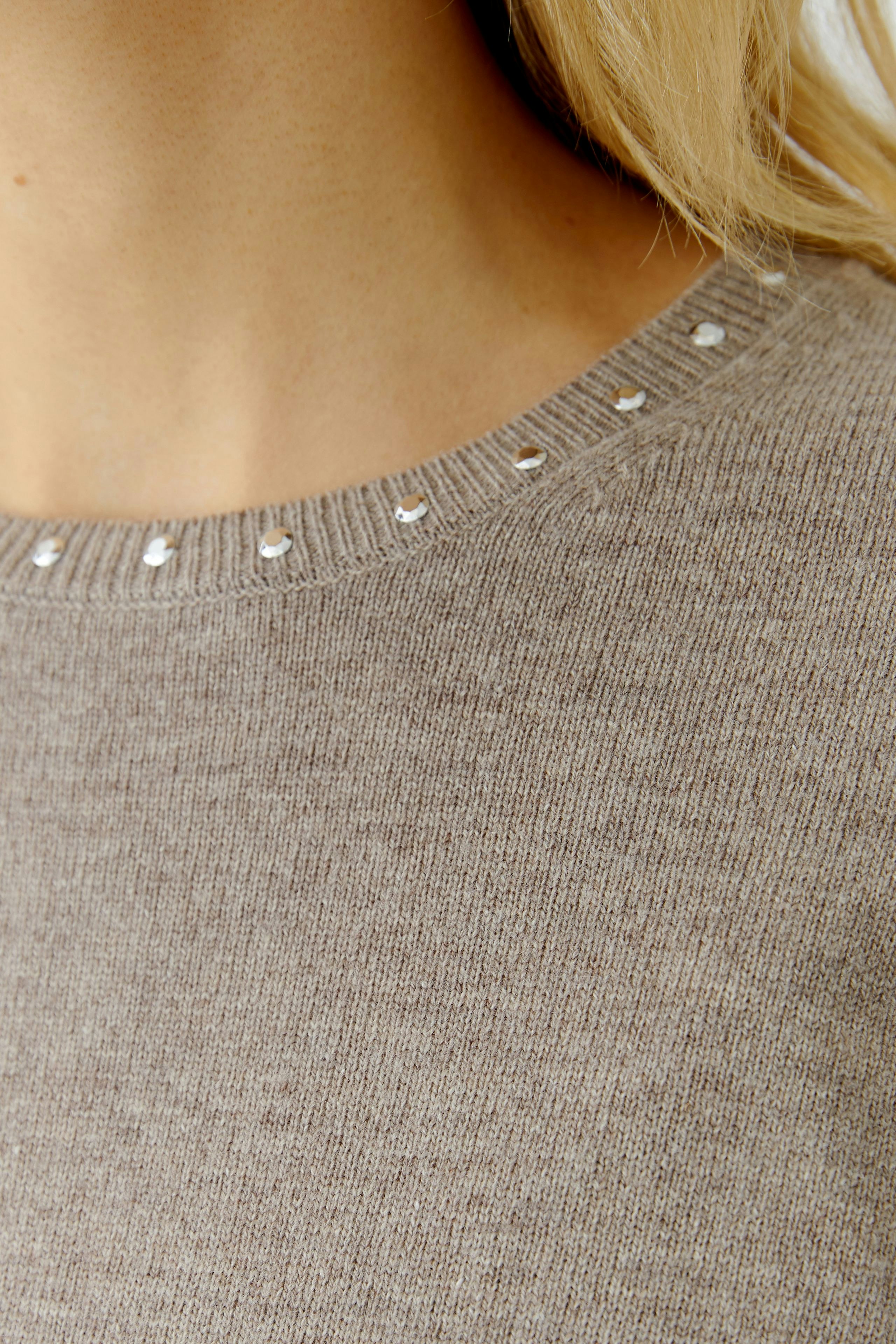 Casual women's pullover: Close-up of a light brown pullover with decorative studs on the neckline.