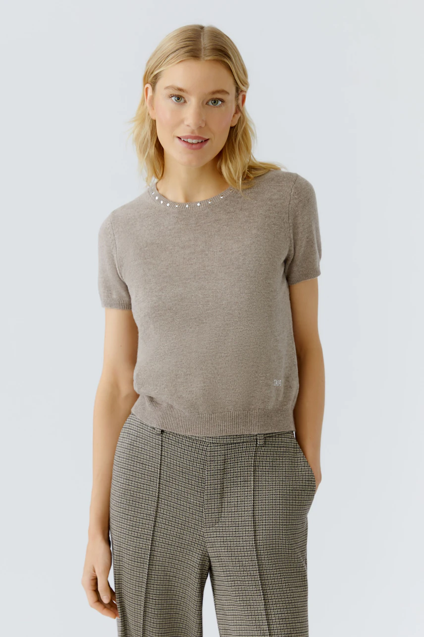 Bequemer Damen-Pullover in Beige mit kurzen Ärmeln und dezenten Details, getragen von einer Frau.