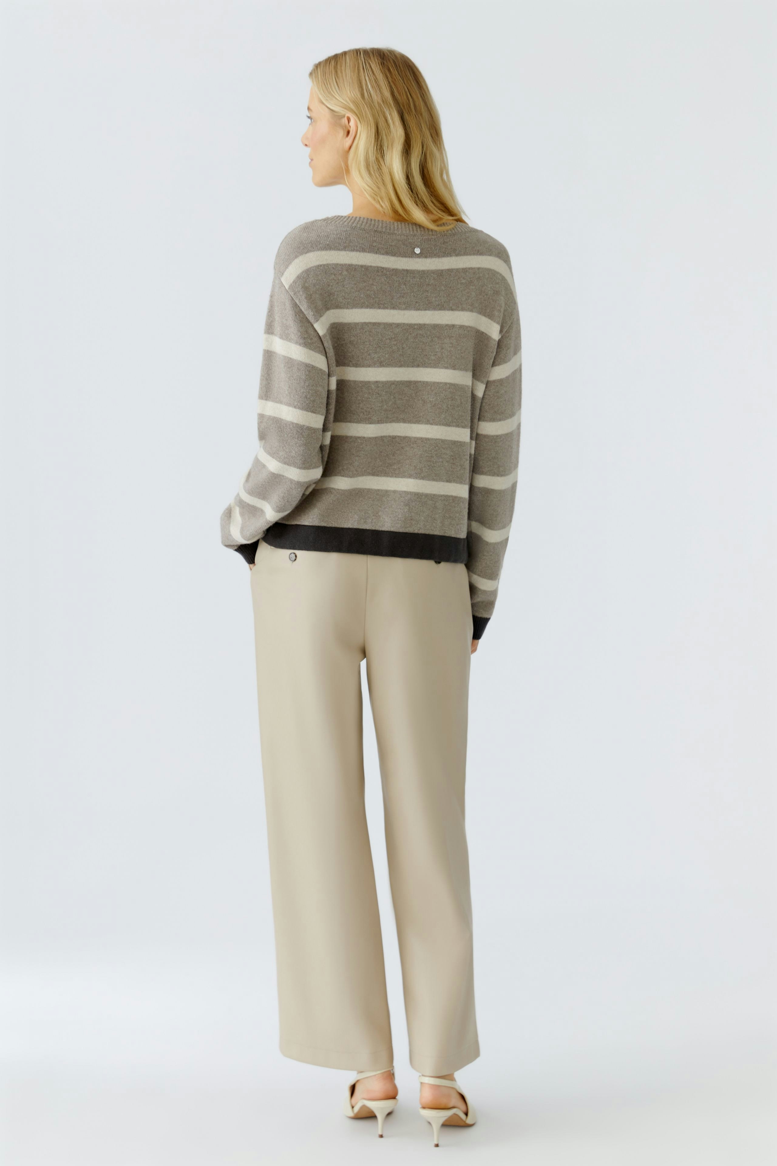 Damen-Pullover: Frau mit gestreiftem Pullover in Grau und Schwarz, lässig und modern.