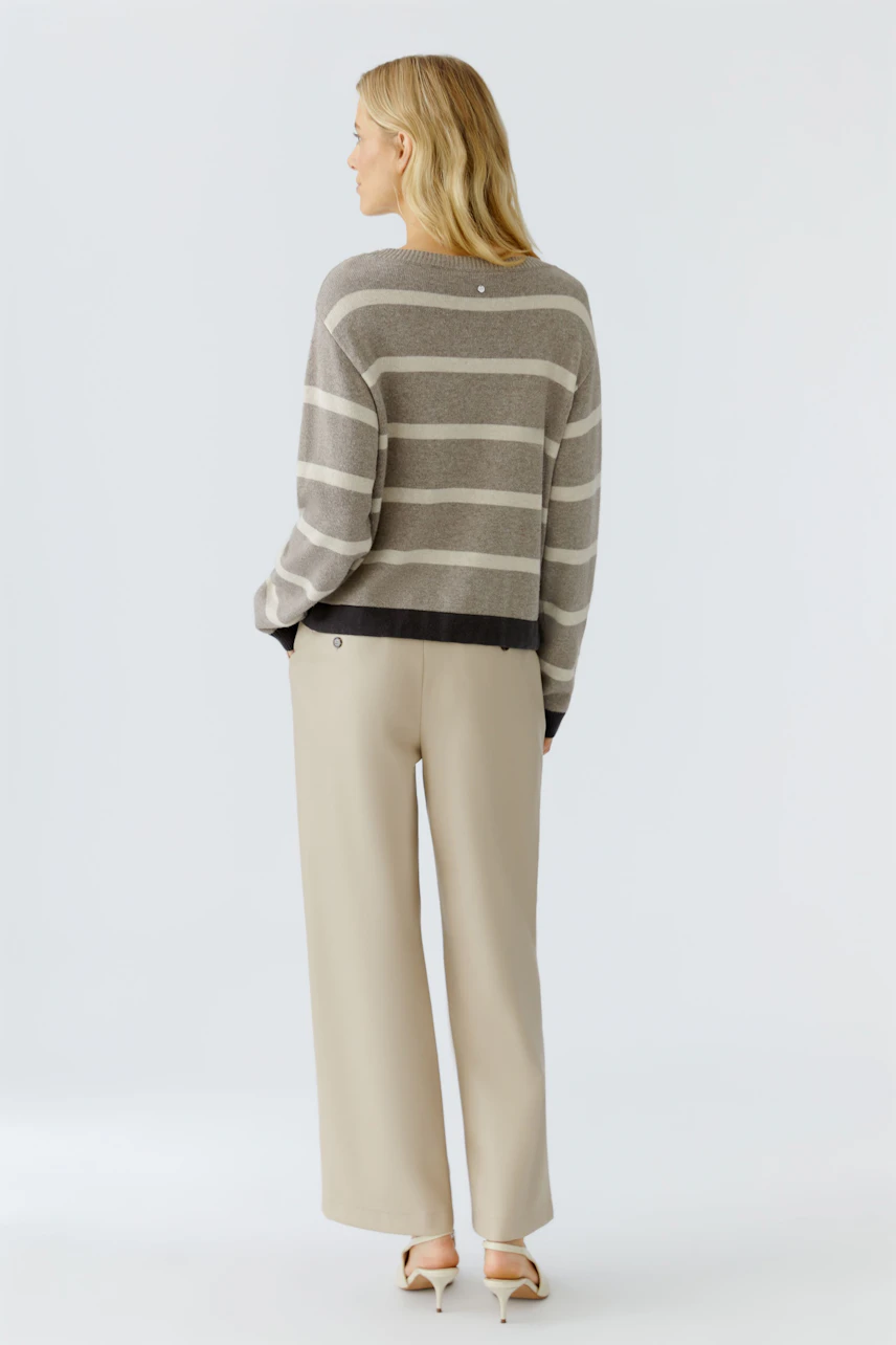 Damen-Pullover: Frau mit gestreiftem Pullover in Grau und Schwarz, lässig und modern.