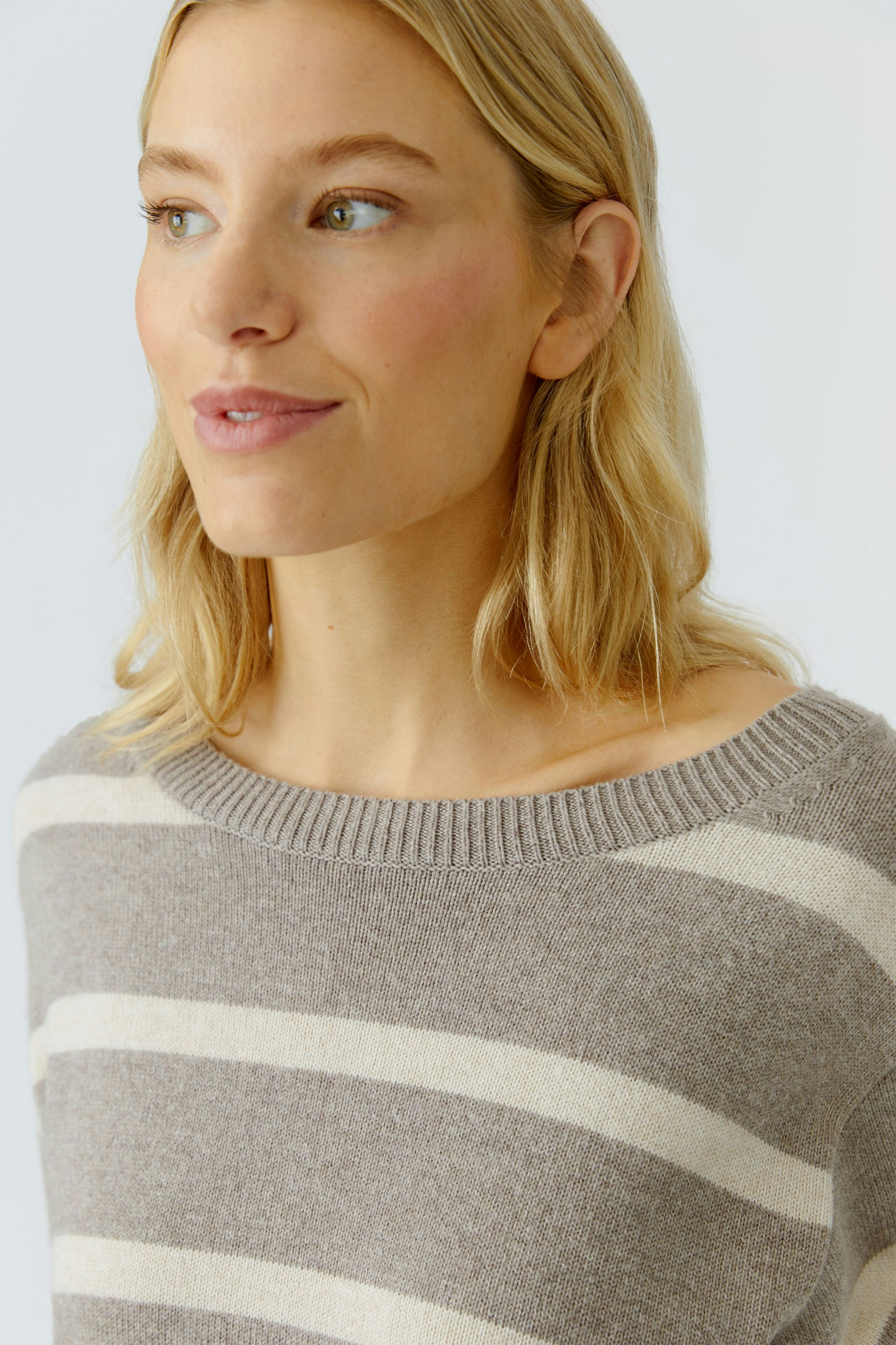 Damen-Pullover: Frau mit gestreiftem Pullover in Grau und Beige, lässiger Look.