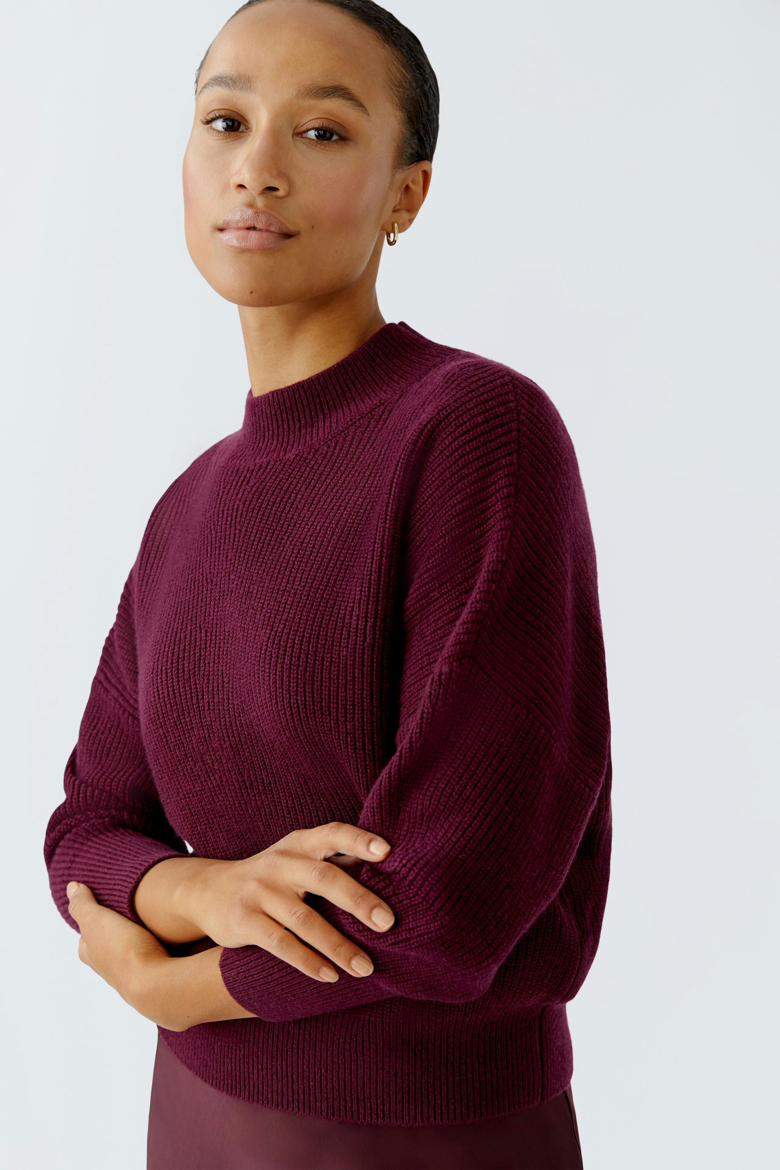 Damen-Pullover: Junge Frau in einem weinroten Strickpullover mit lässigem Schnitt und Rundhalsausschnitt.