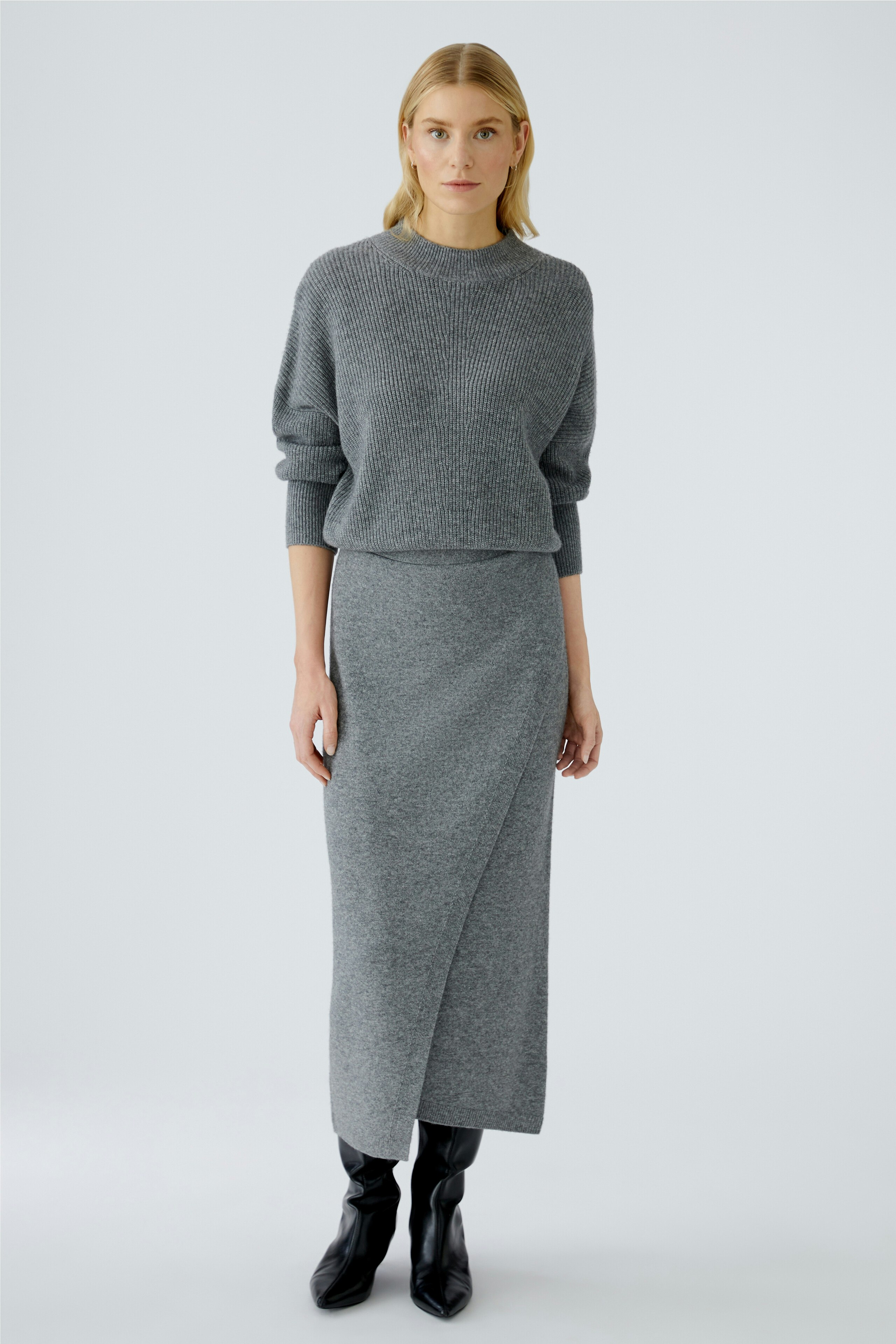 Casual women's pullover: A woman in a gray pullover with a relaxed fit, paired with a matching skirt.