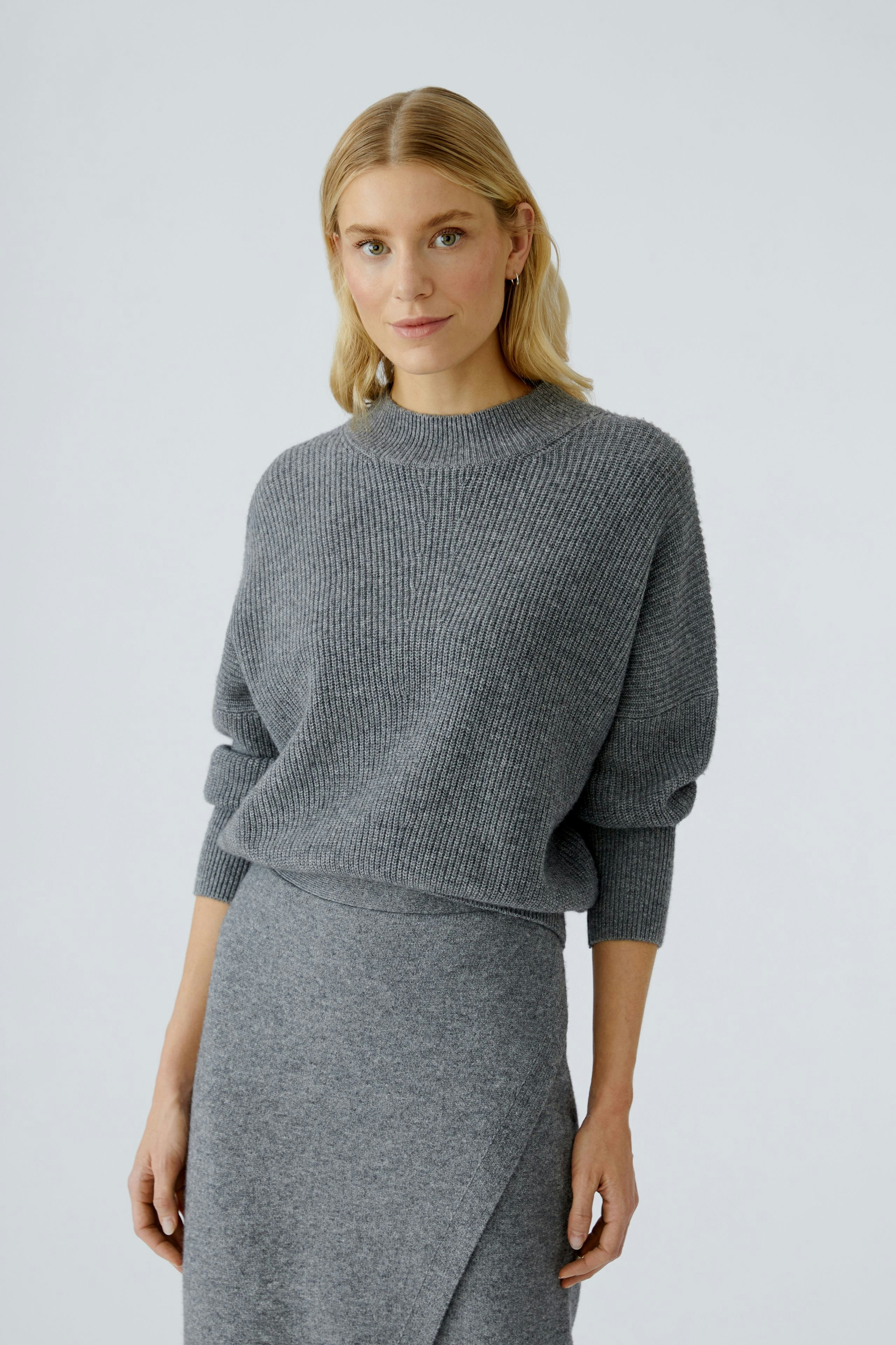 Casual women's pullover: A woman in a cozy gray pullover with a relaxed fit and ribbed texture.