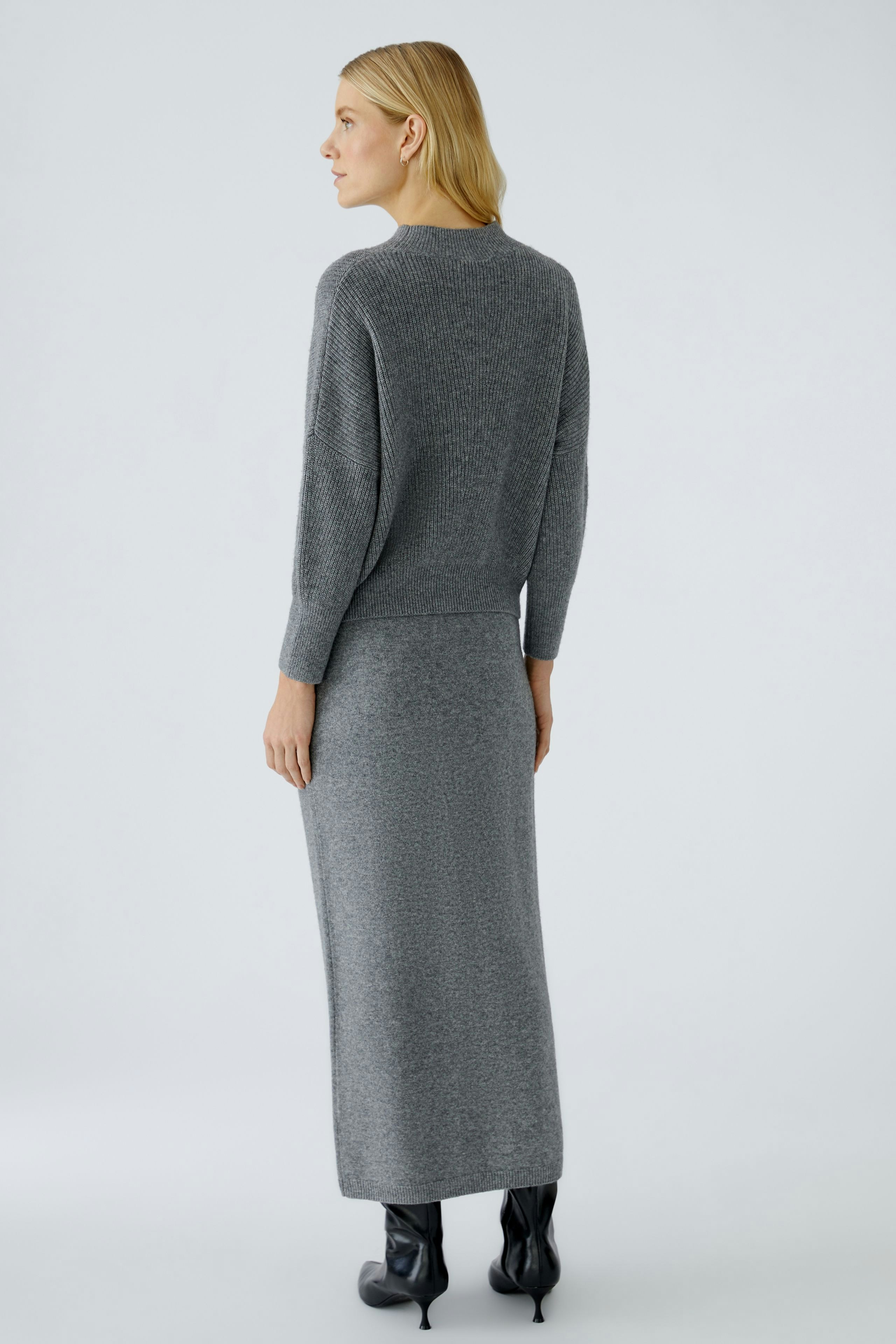 Casual women's pullover: A woman in a gray knitted pullover paired with a matching skirt.