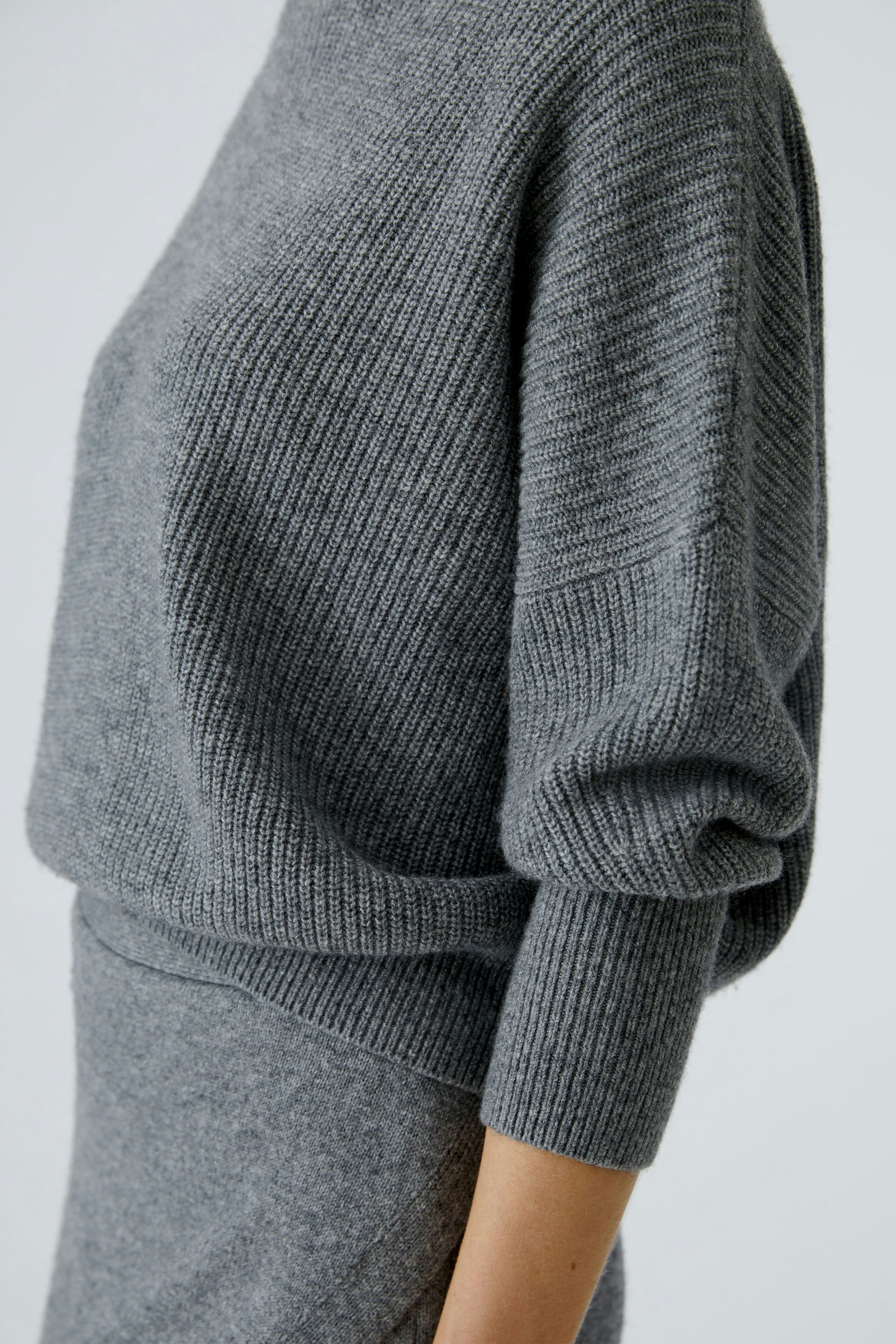 Casual women's pullover: A woman in a cozy gray pullover with a relaxed fit and ribbed texture.