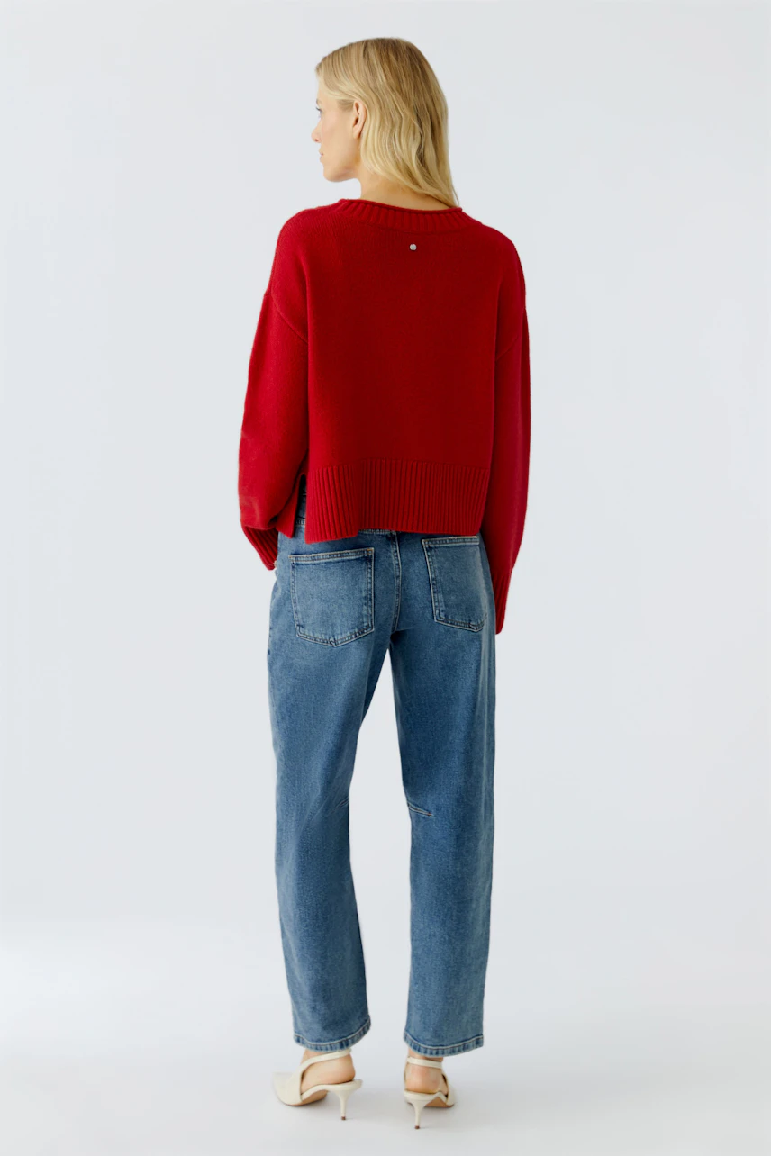 Casual women's pullover: A woman in a red knit pullover paired with relaxed jeans, showcasing a laid-back style.
