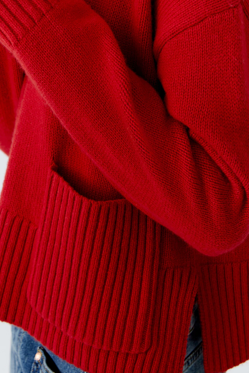 Casual women's pullover: A woman in a cozy red pullover with ribbed details and pockets.