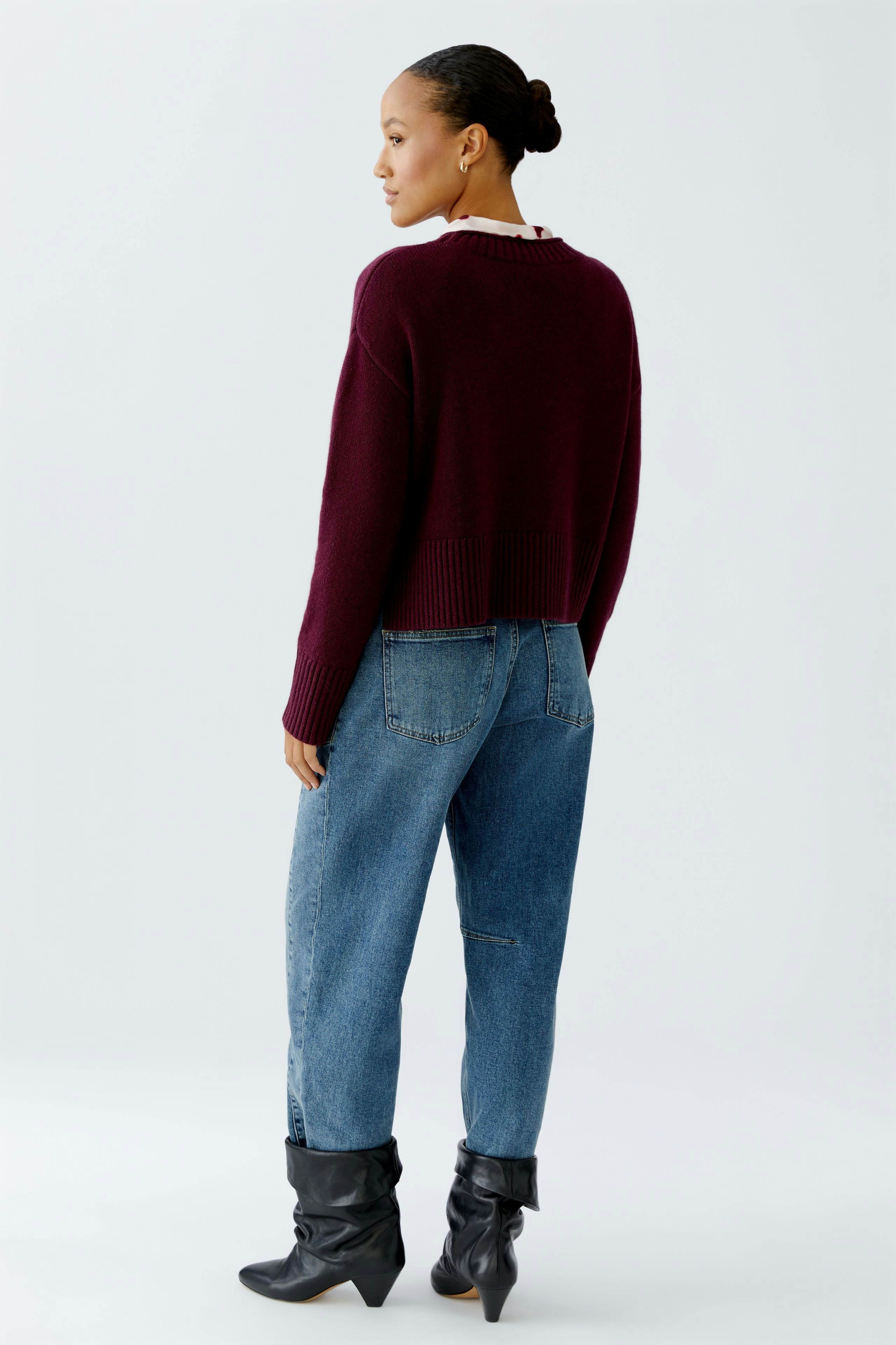 Casual women's pullover: A woman in a burgundy cropped pullover paired with high-waisted jeans.