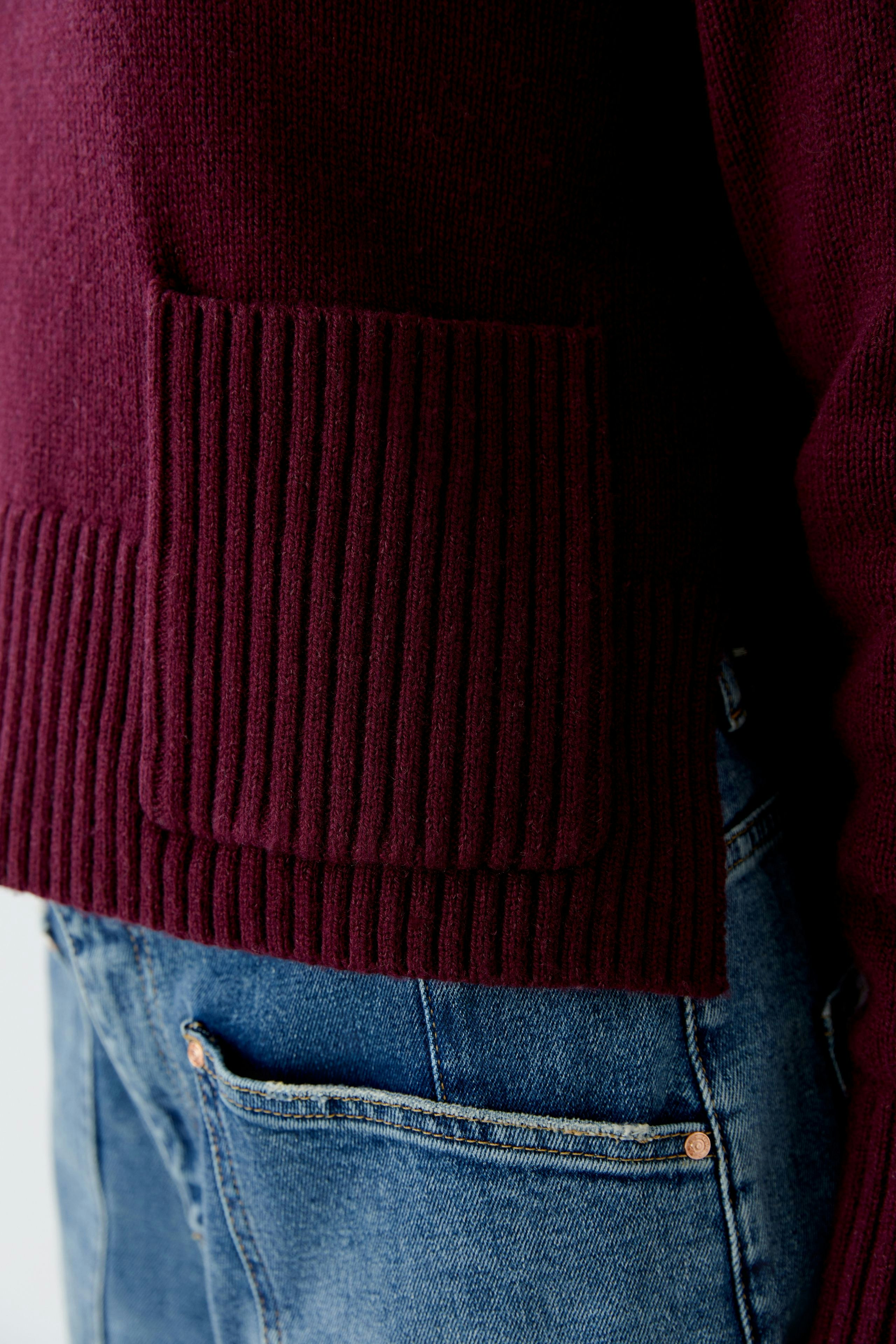 Casual women's pullover in deep burgundy with ribbed detailing, paired with denim jeans.
