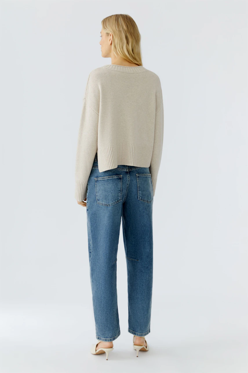 Casual women's pullover: A woman in a light beige pullover paired with relaxed-fit jeans.