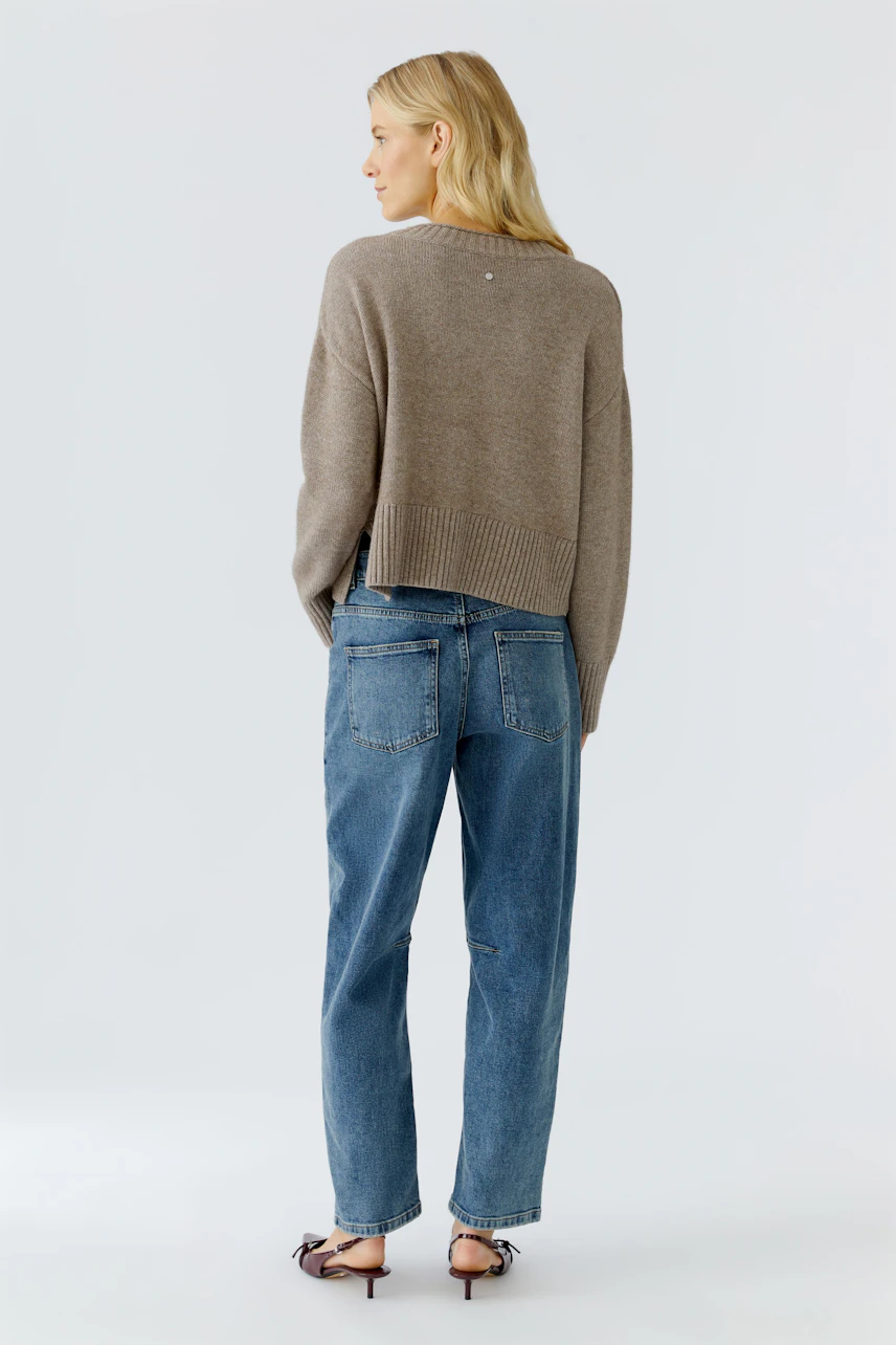 Casual women's pullover: A woman in a cozy brown pullover paired with relaxed blue jeans.