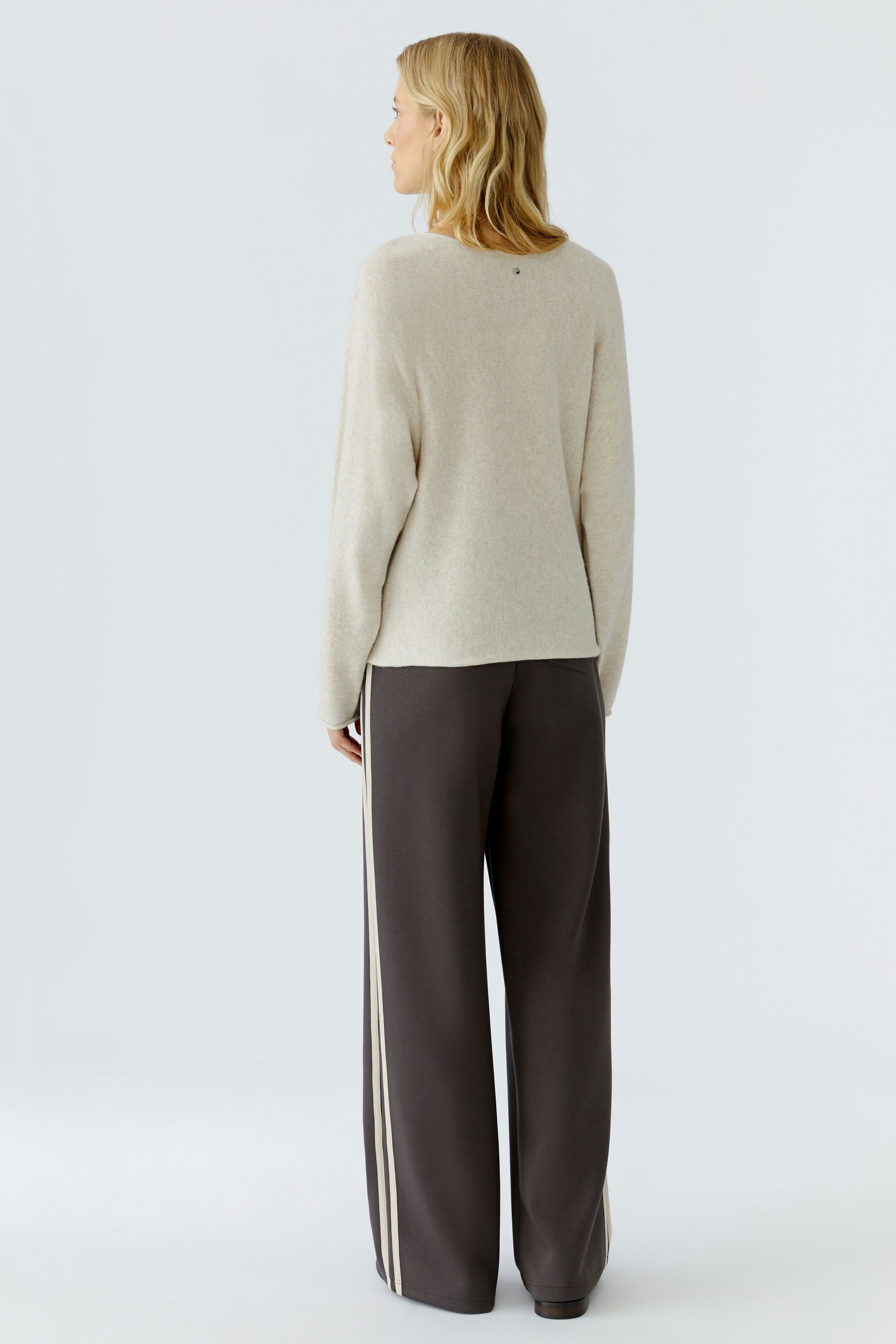 Casual women's pullover: A woman in a beige pullover paired with wide-leg pants, showcasing a relaxed style.