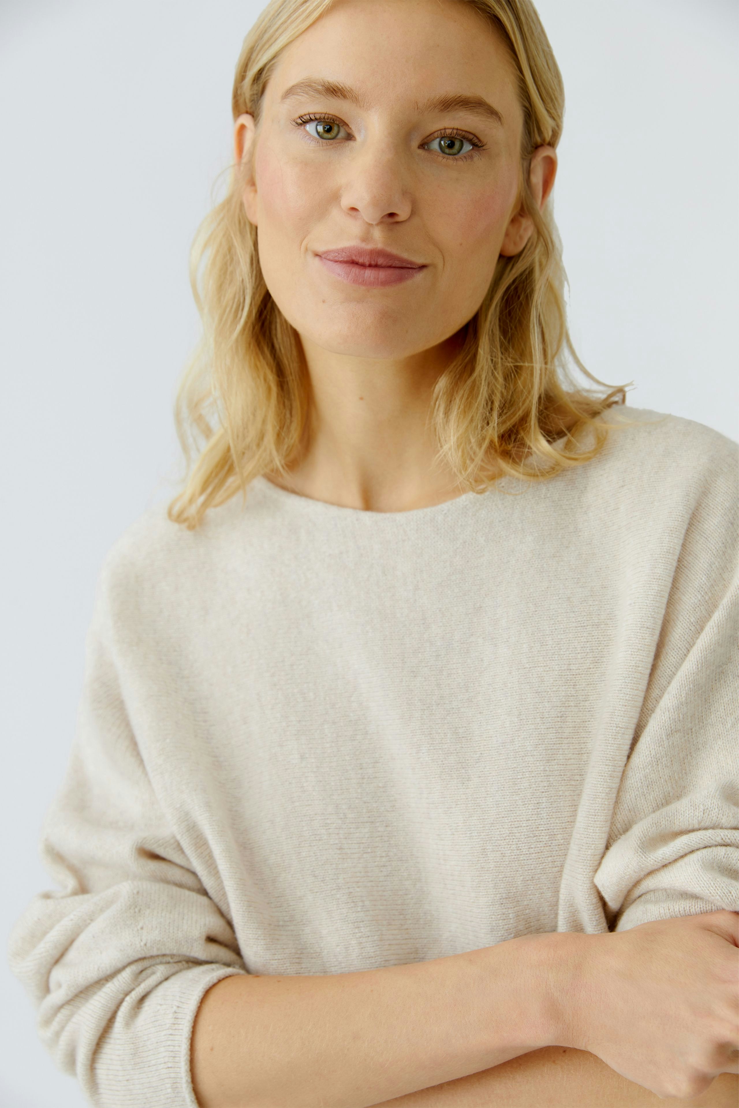 Casual women's pullover: Young woman in a soft beige pullover, smiling and relaxed.