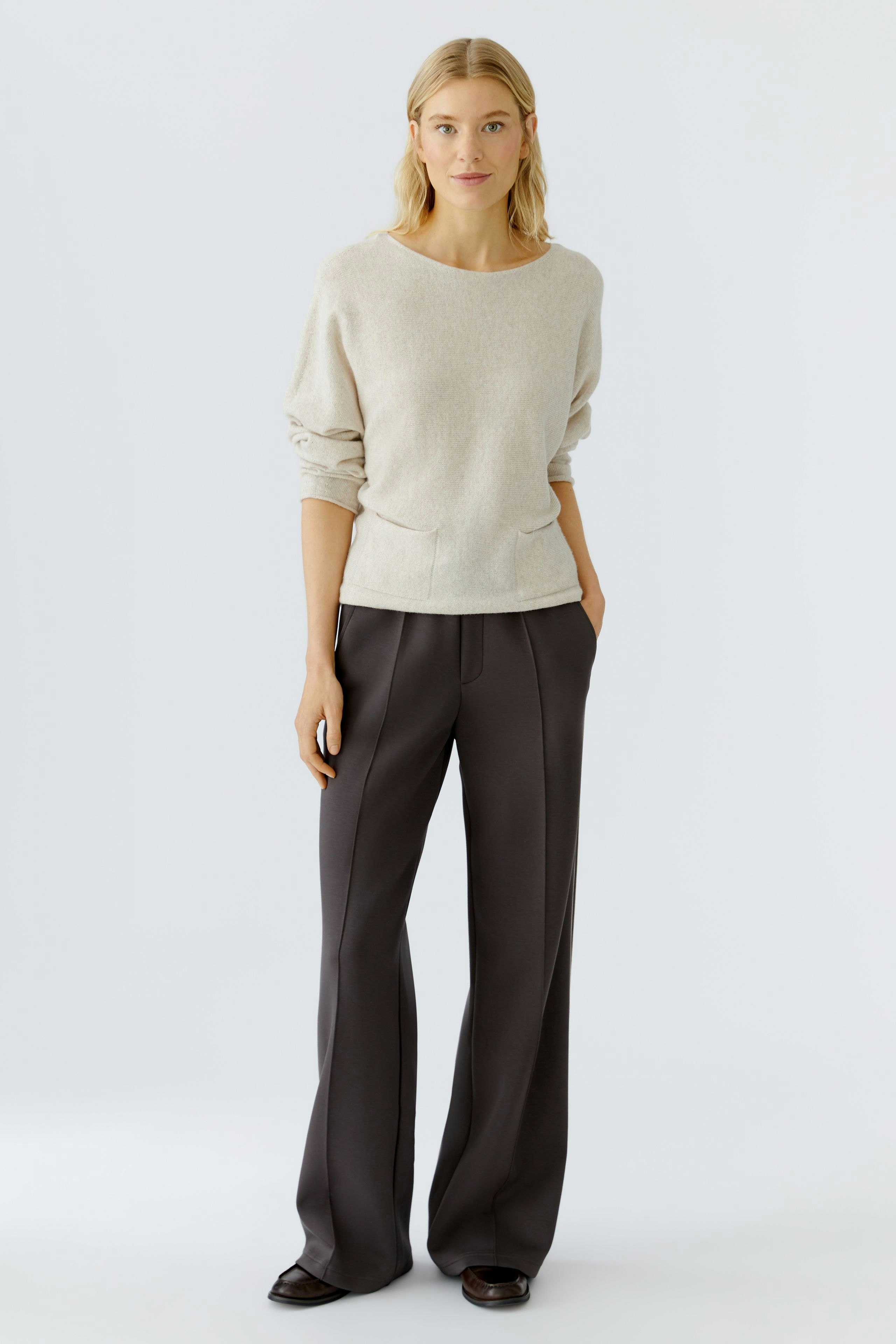Casual women's pullover: A woman in a light beige pullover with a relaxed fit and pockets.