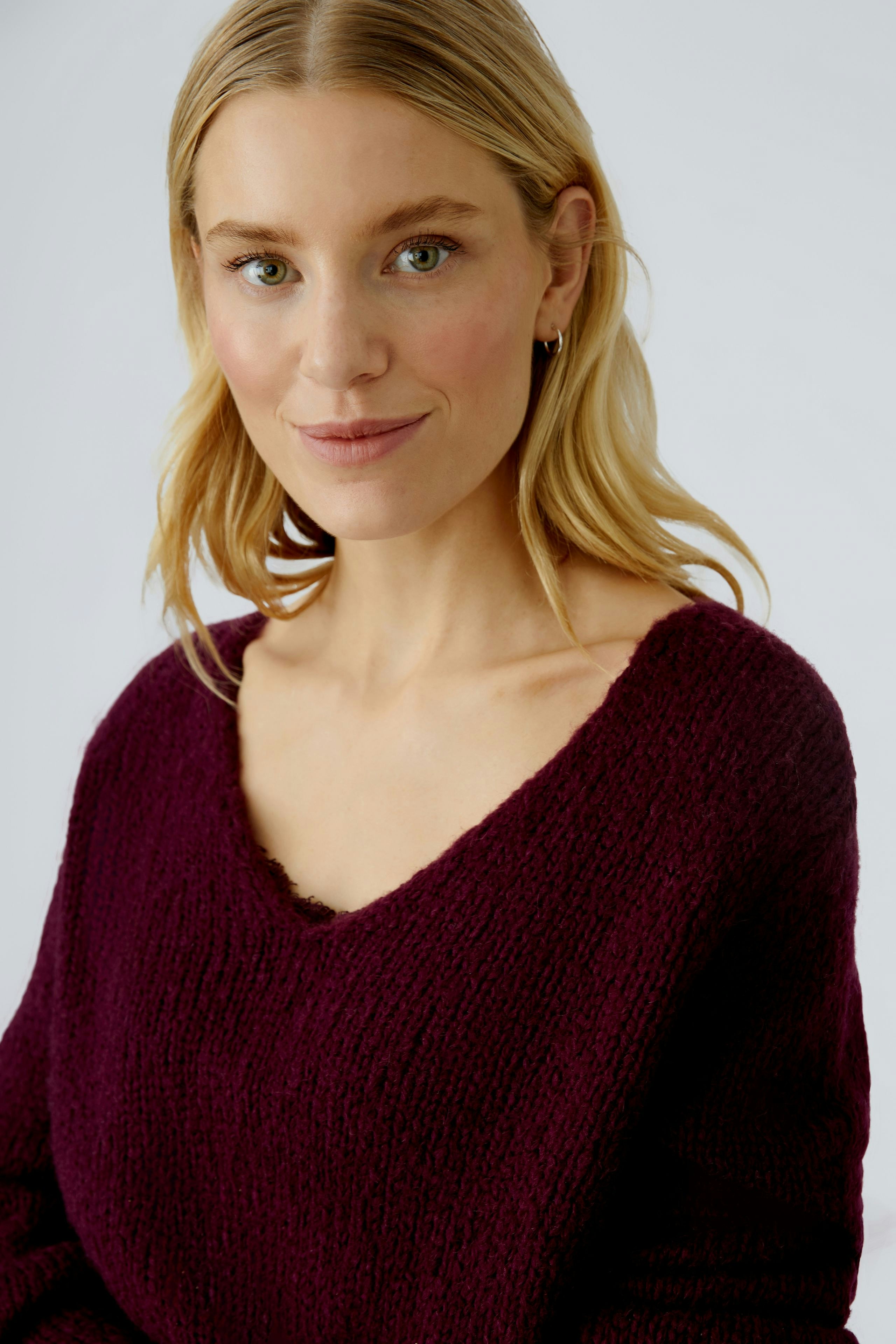 Casual women's pullover: Young woman in a deep burgundy knit pullover with a relaxed fit.