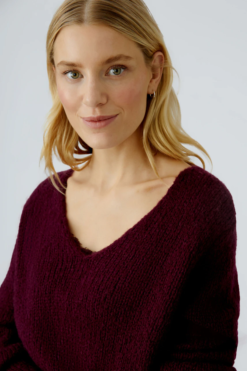Casual women's pullover: Young woman in a deep burgundy knit pullover with a relaxed fit.