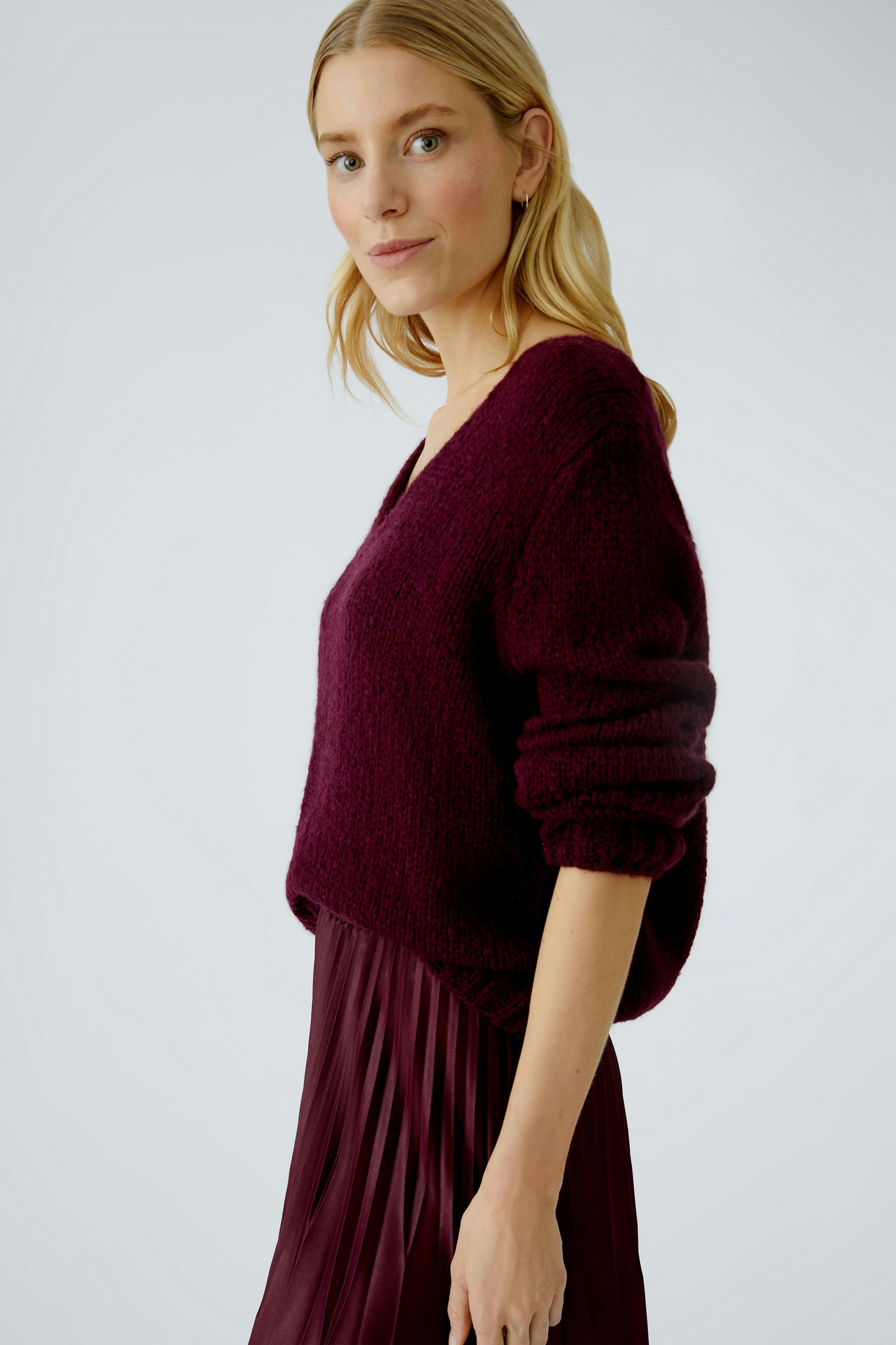 Casual women's pullover: A woman in a deep burgundy pullover with a relaxed fit and voluminous sleeves.