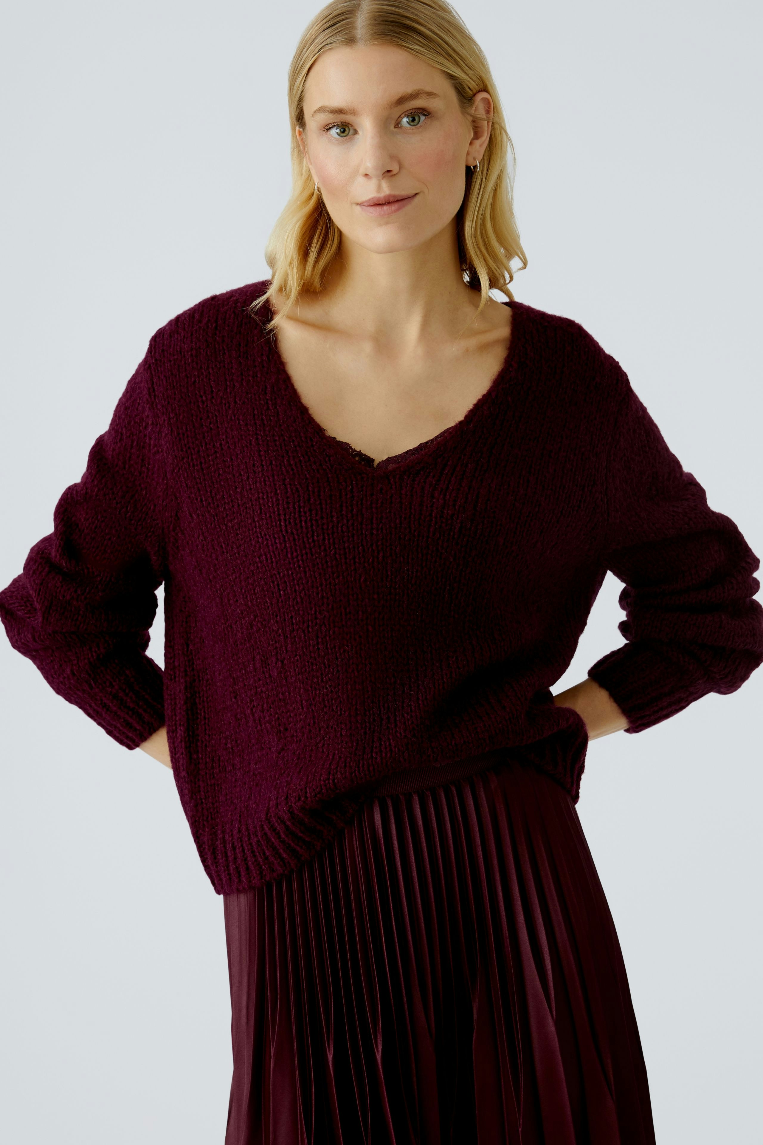 Casual women's pullover: A woman in a deep burgundy knit pullover with a V-neck and relaxed fit.