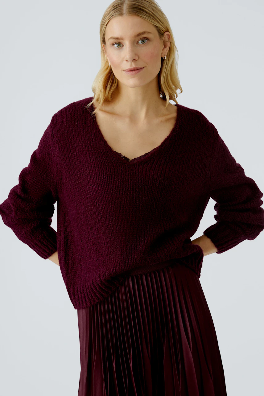 Casual women's pullover: A woman in a deep burgundy knit pullover with a V-neck and relaxed fit.